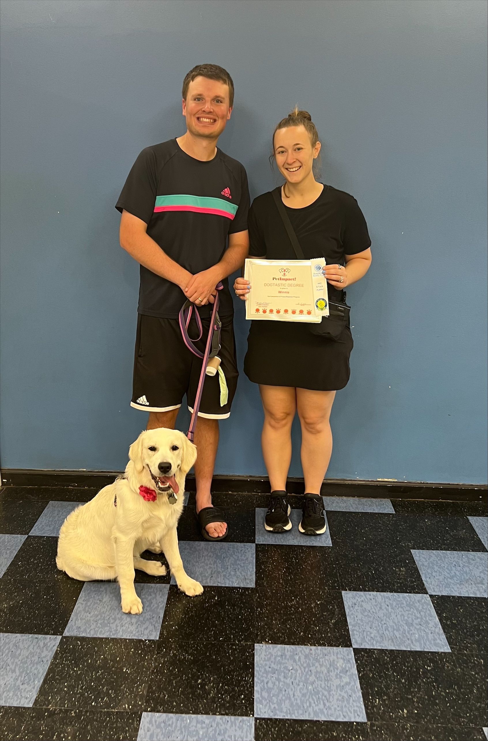 A man and a woman are standing next to a dog on a leash.