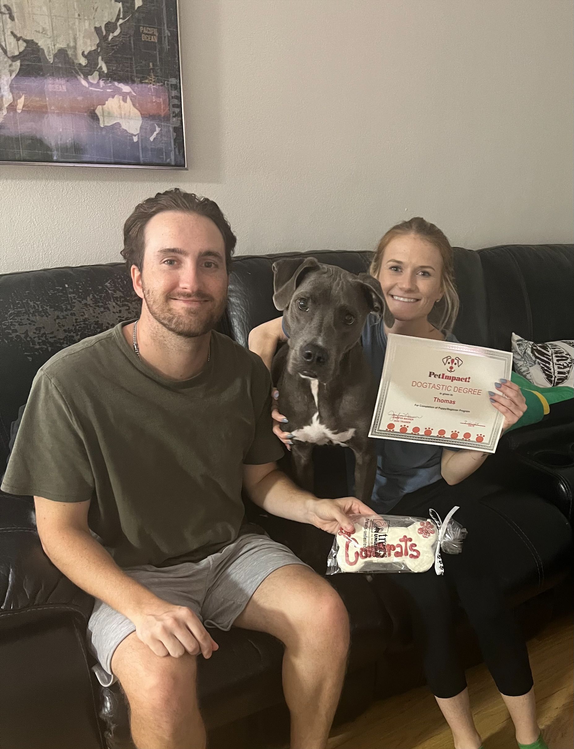 A man and a woman are sitting on a couch with a dog.