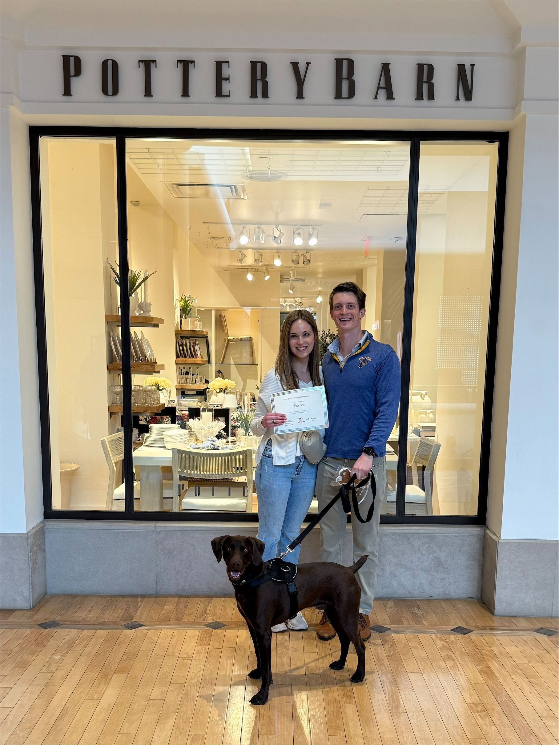 A man and woman standing with a dog and certificate