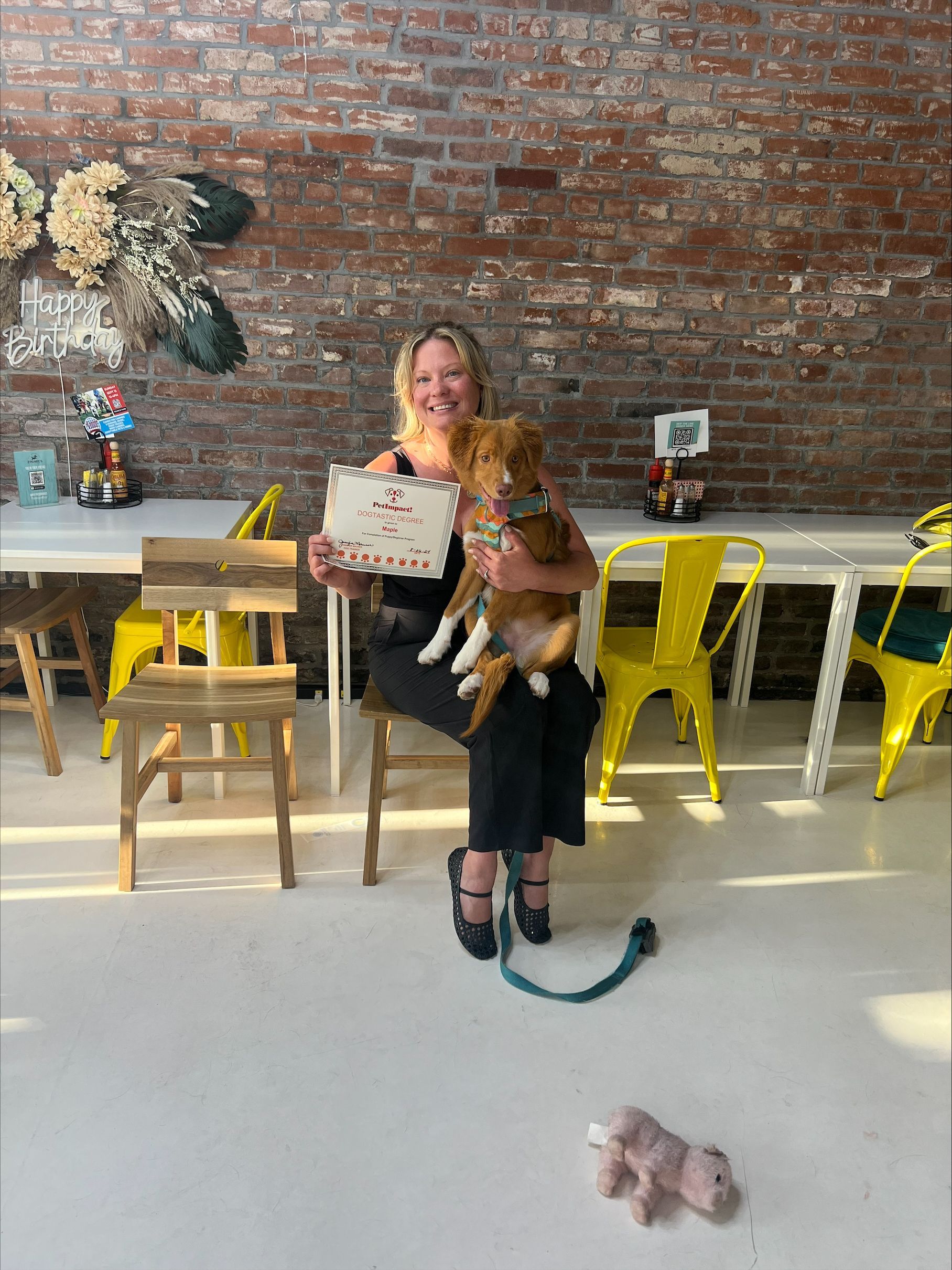 A woman is sitting on a chair holding a dog.