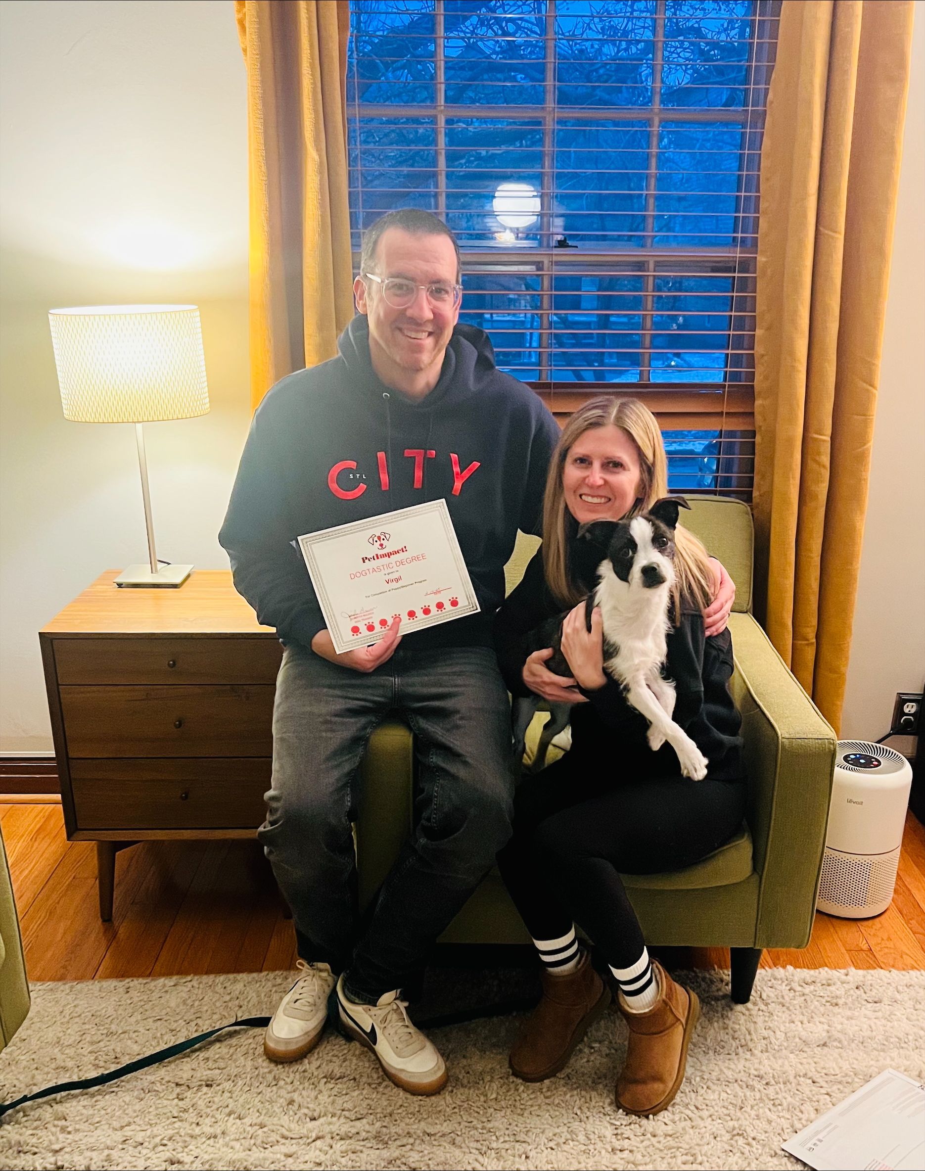 A man and a woman are sitting in a chair with a dog.