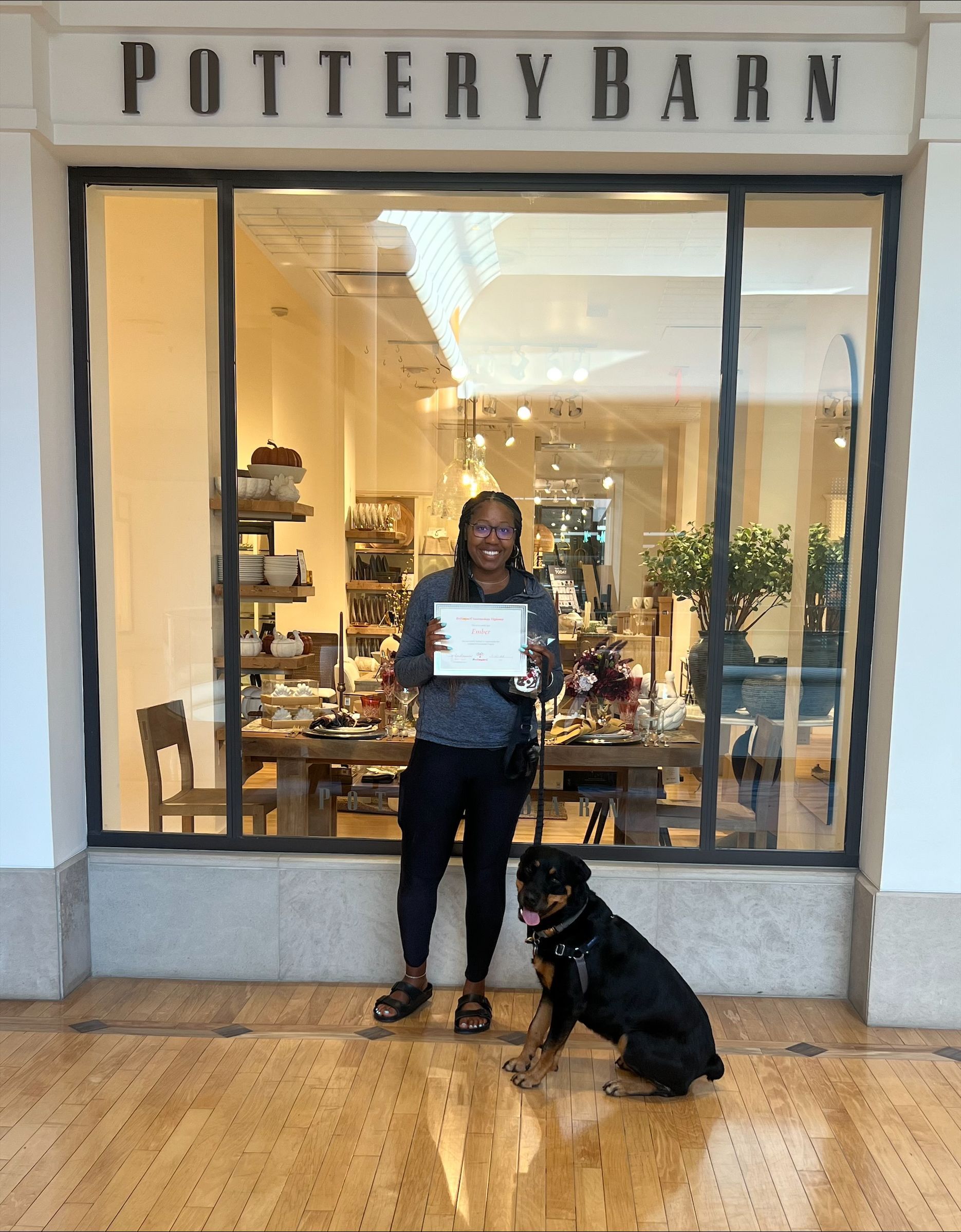 A woman and a dog are standing in front of a pottery barn store.