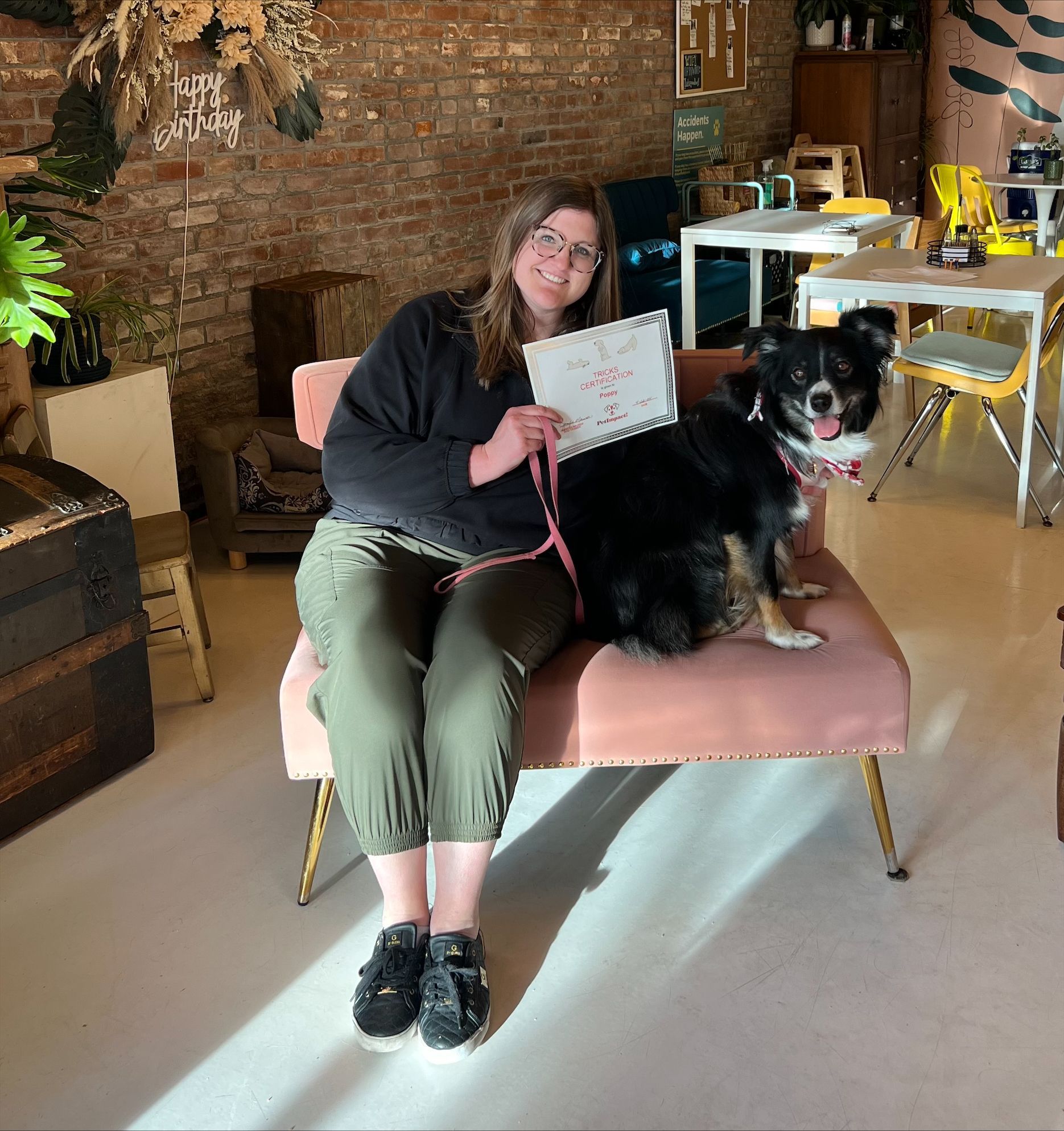 A woman is sitting on a chair with a black dog