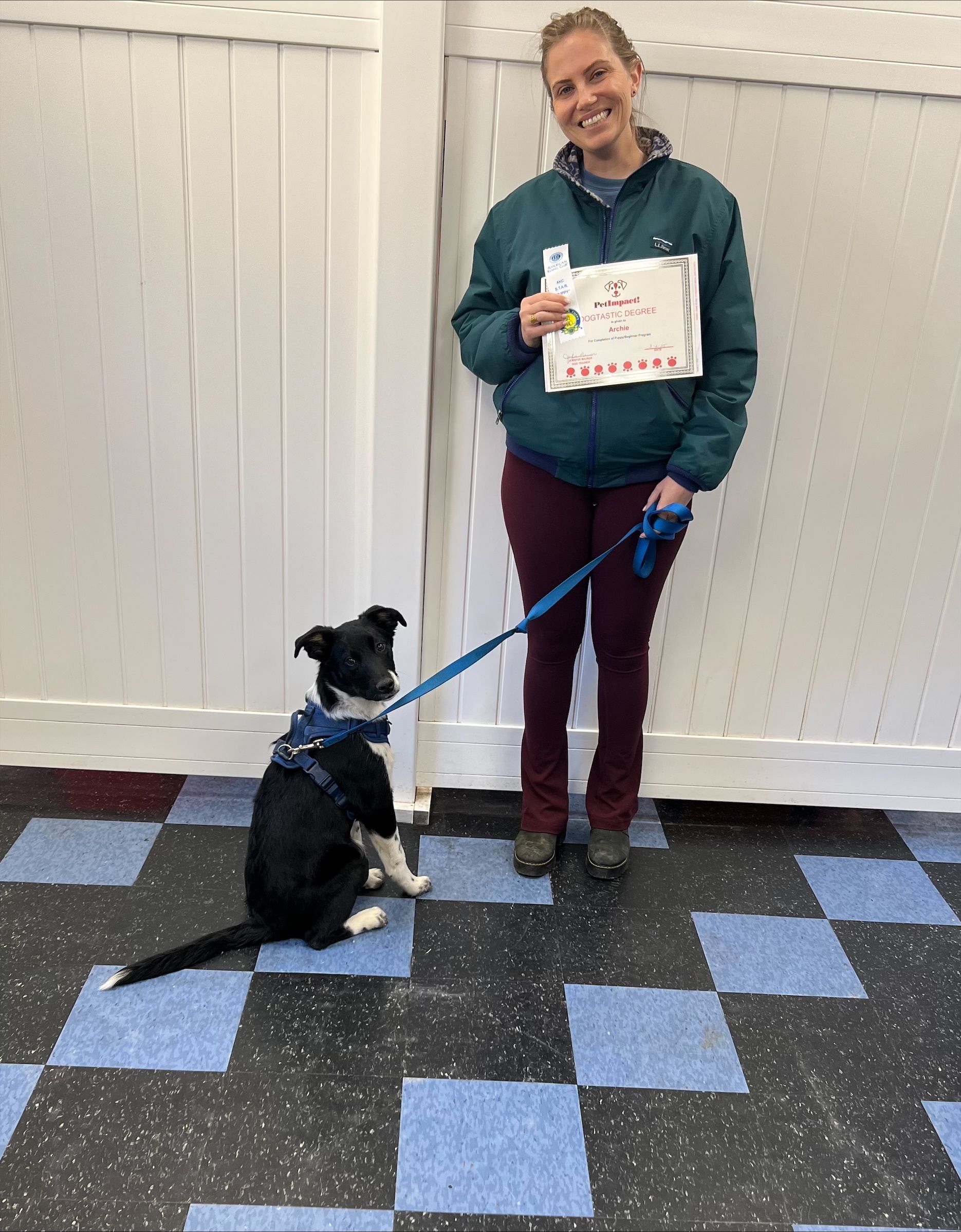 A woman is standing next to a small black and white dog on a leash.
