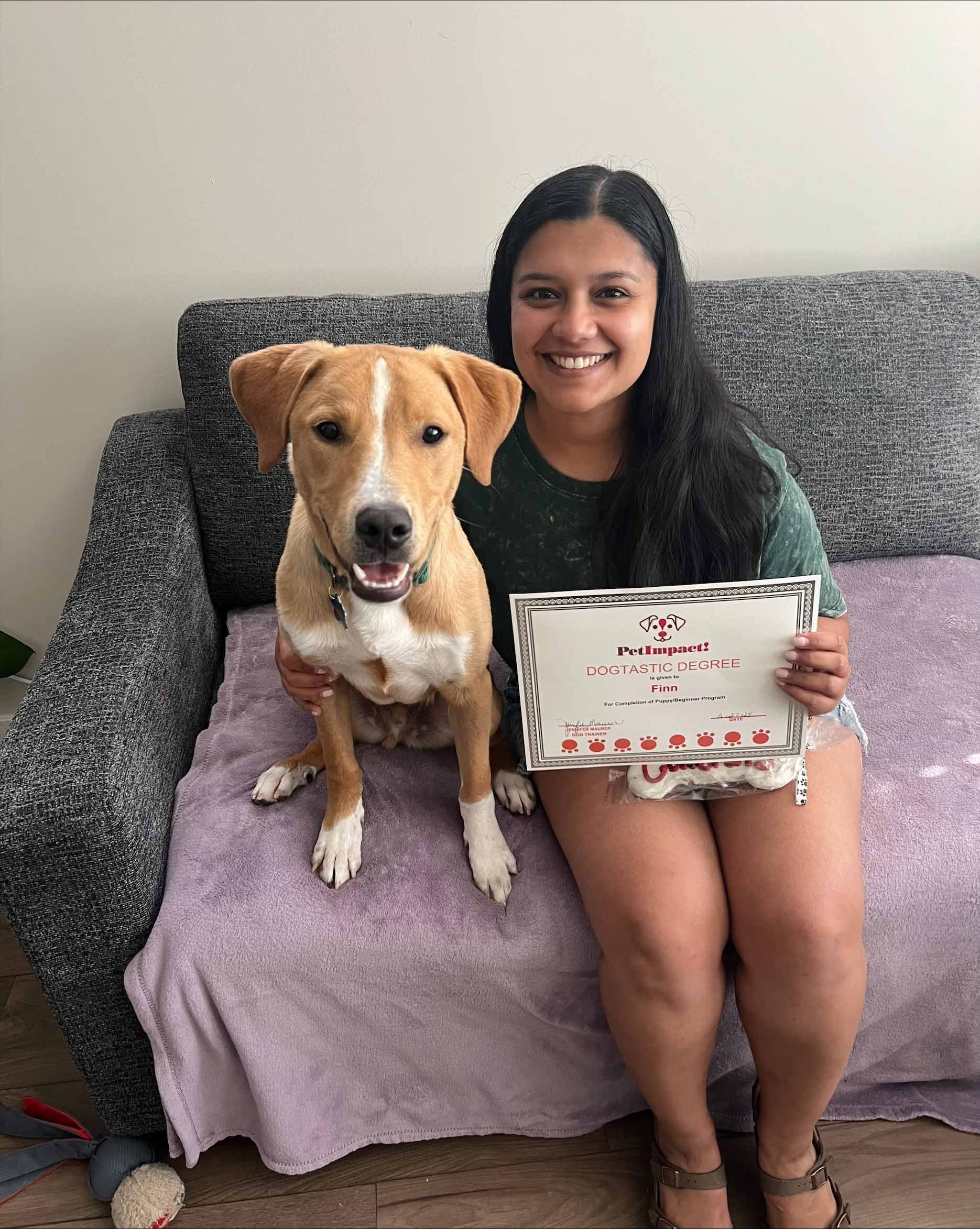 A Woman Is Sitting On A Couch With A Dog And Holding A Certificate