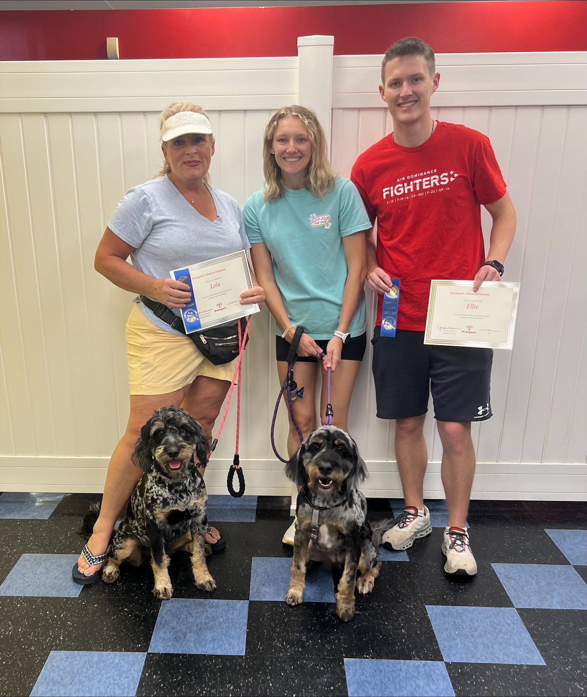 A group of people standing next to two dogs holding awards.