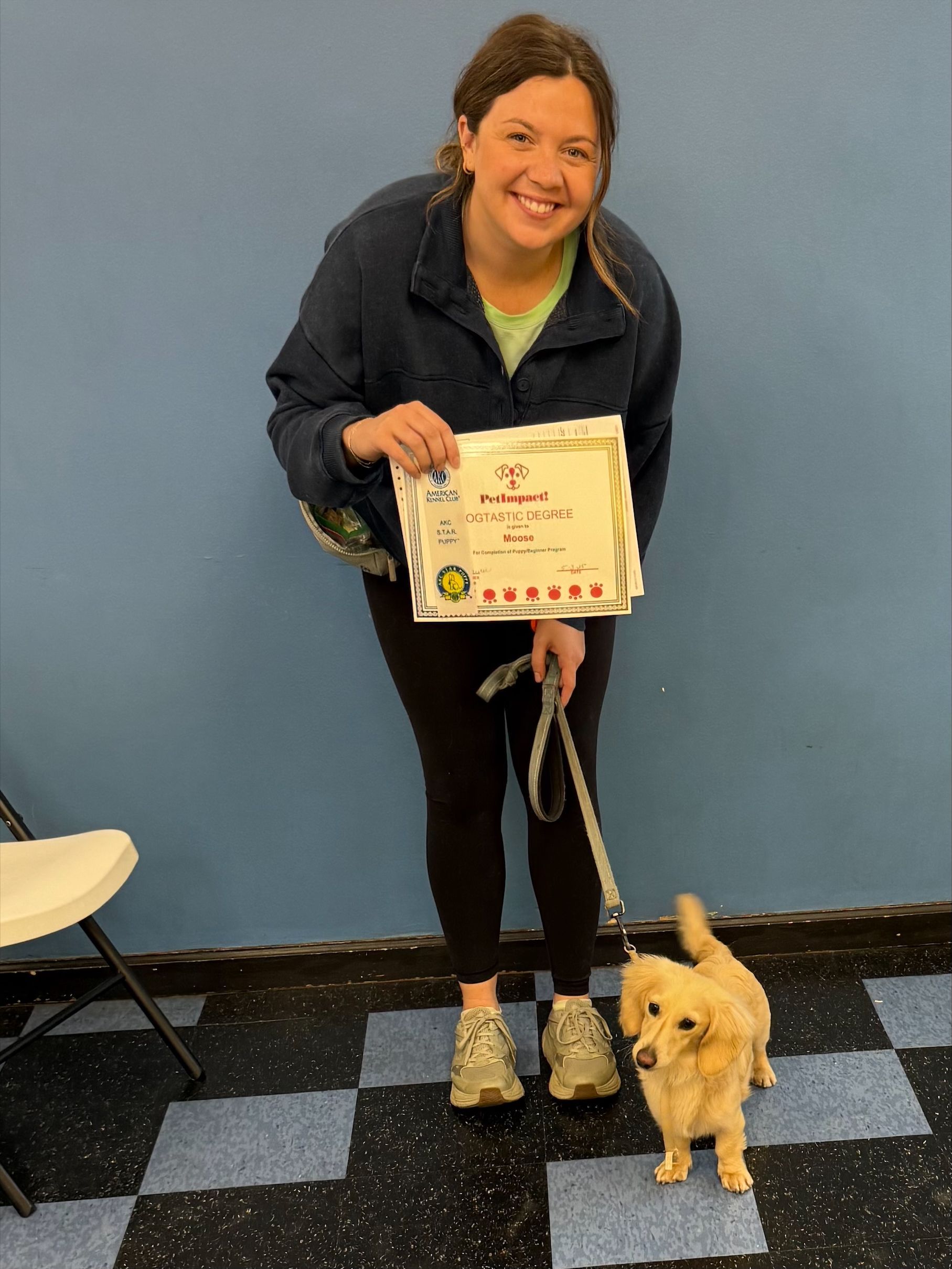 A woman is holding a cake and a dog on a leash
