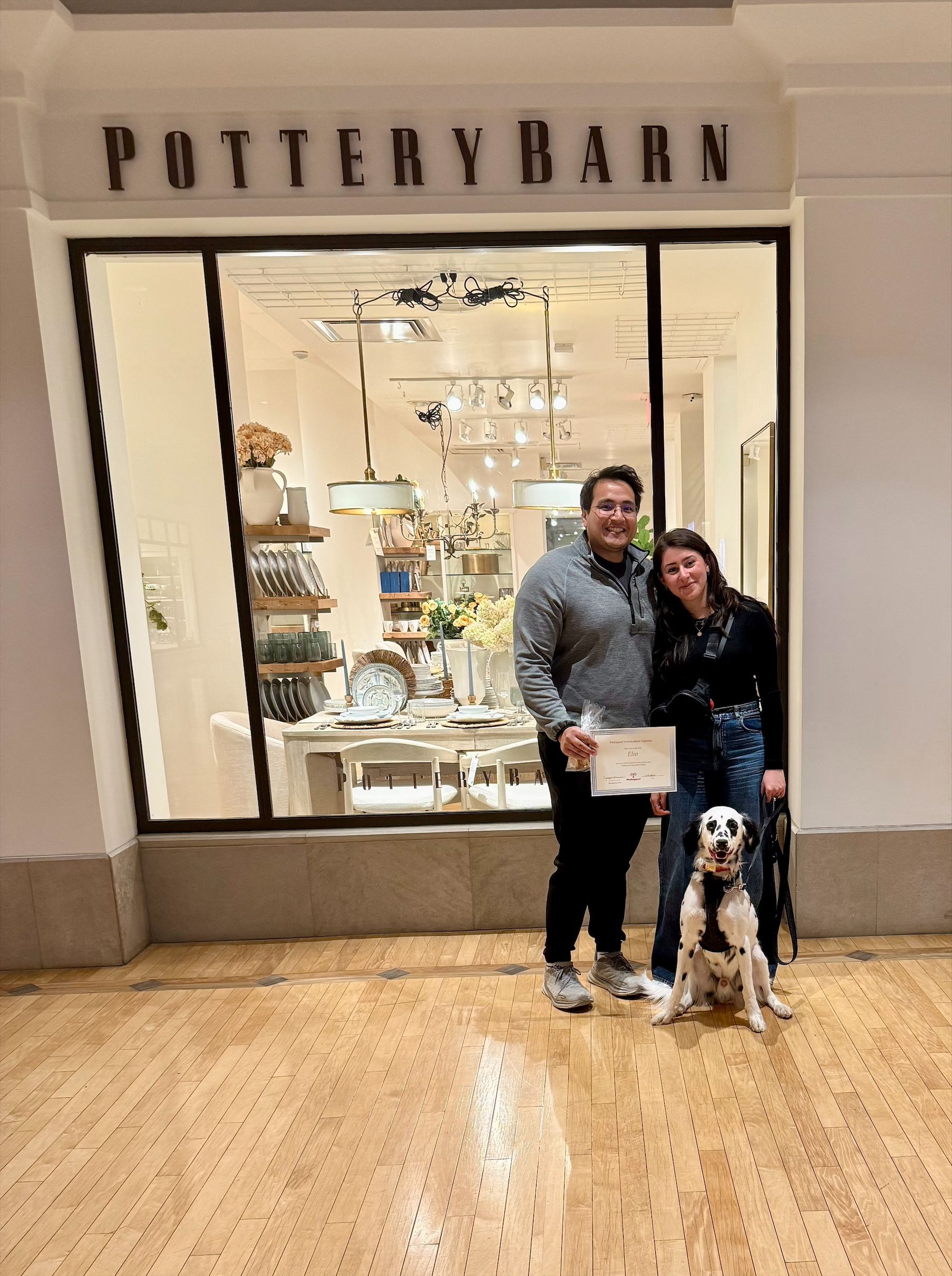 Couple with dog posing in front of Pottery Barn storefront.