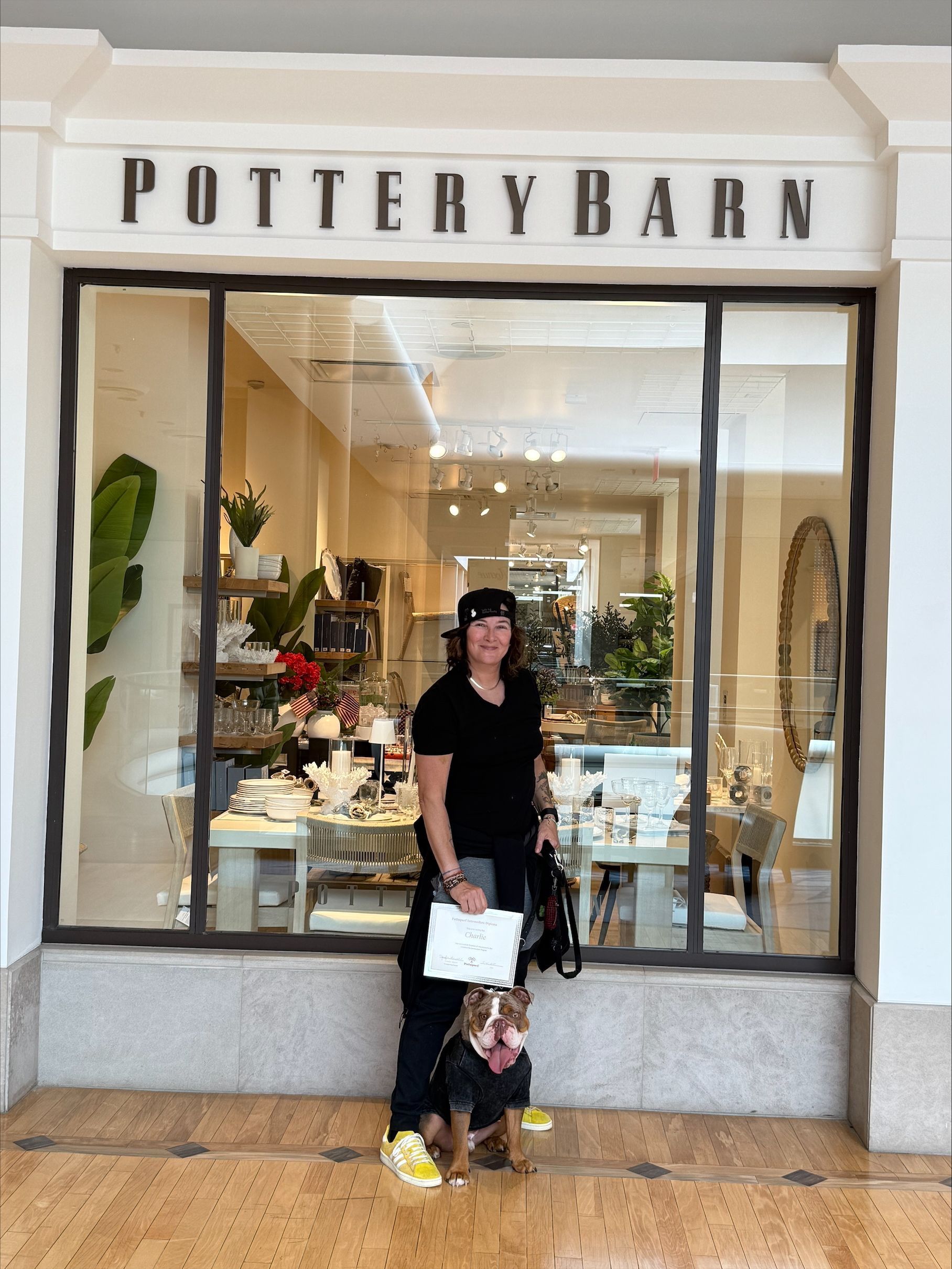A woman and a dog are standing in front of a pottery barn store.