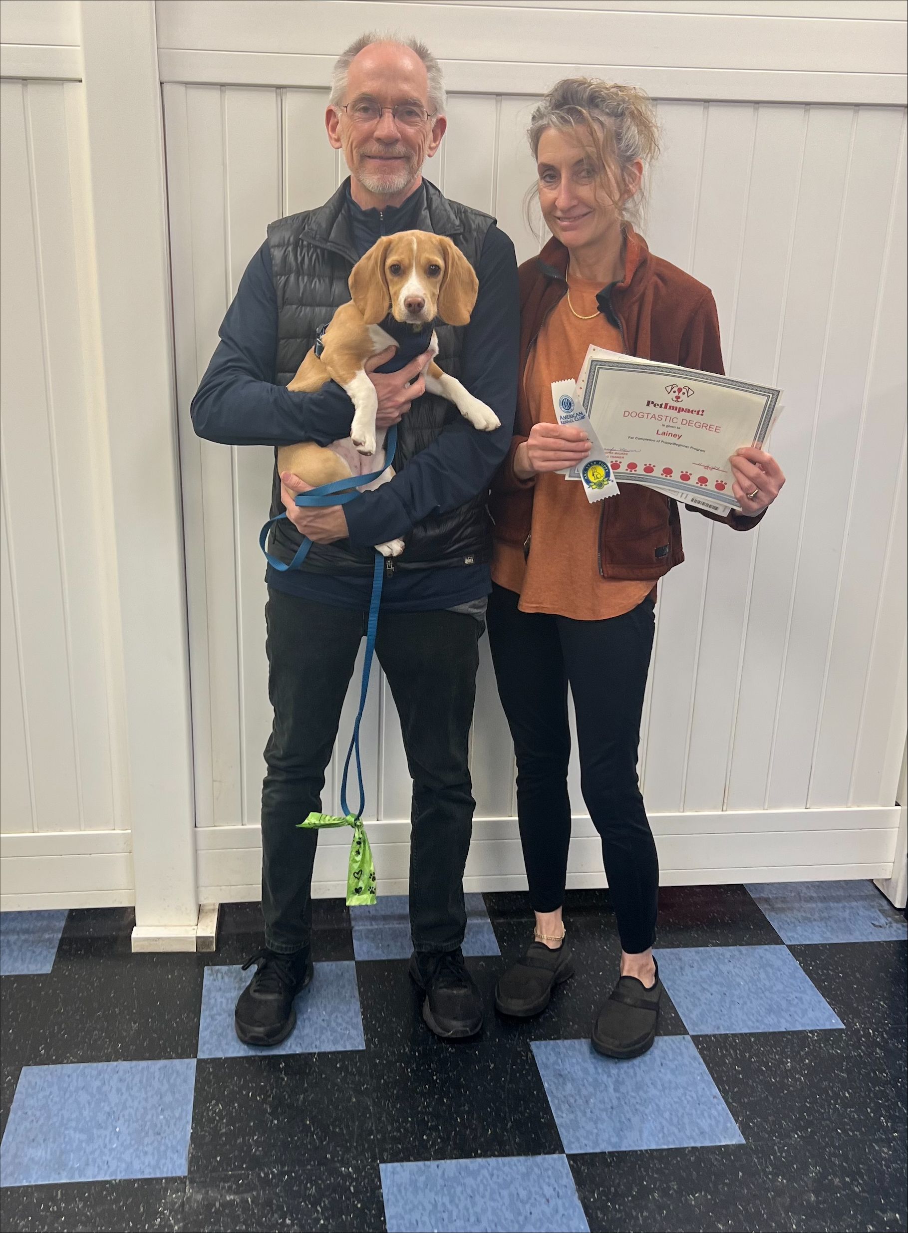 A Man and A Woman Are Holding a Puppy and A Certificate.