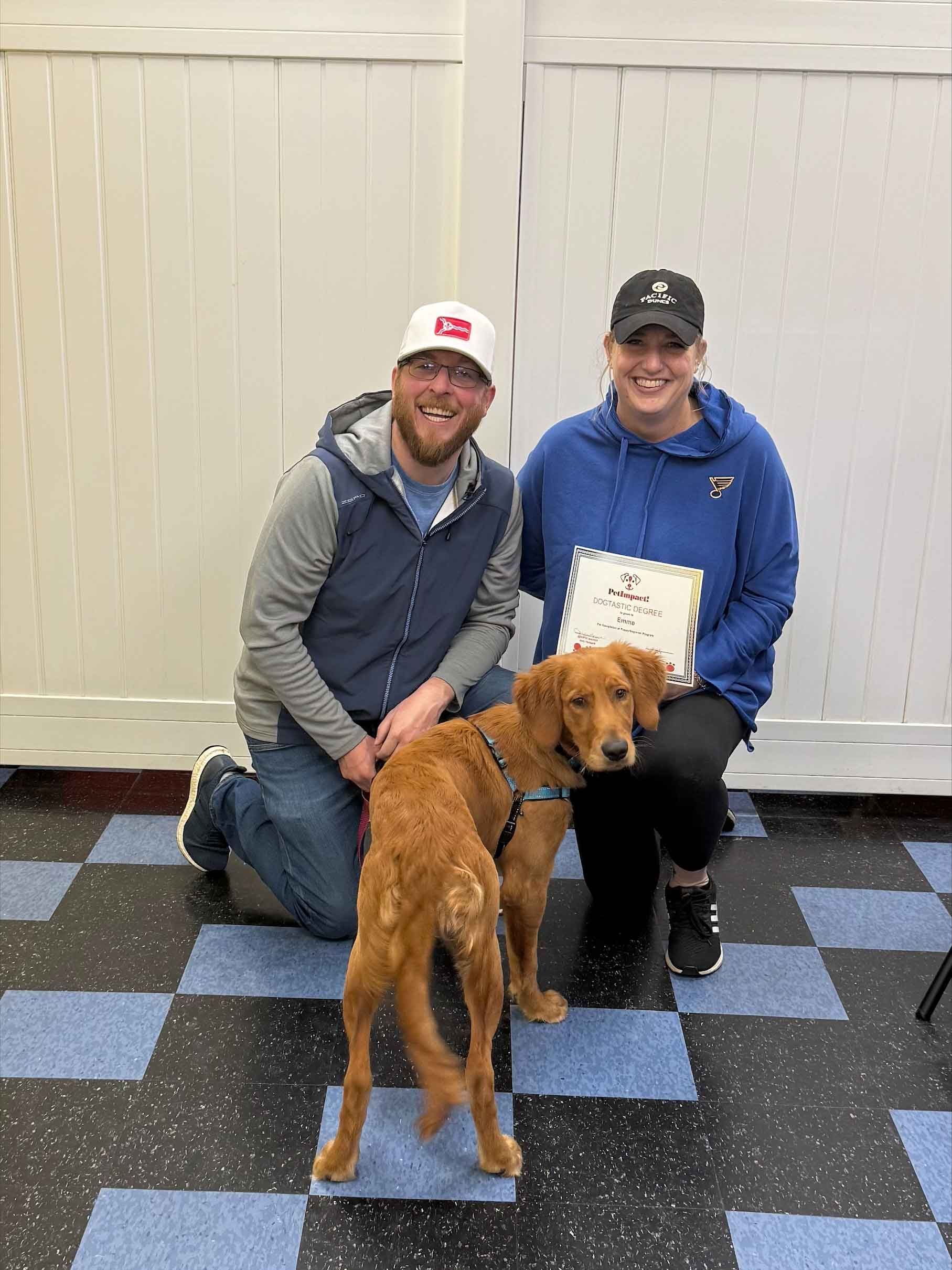 A man and a woman are kneeling down next to a dog.