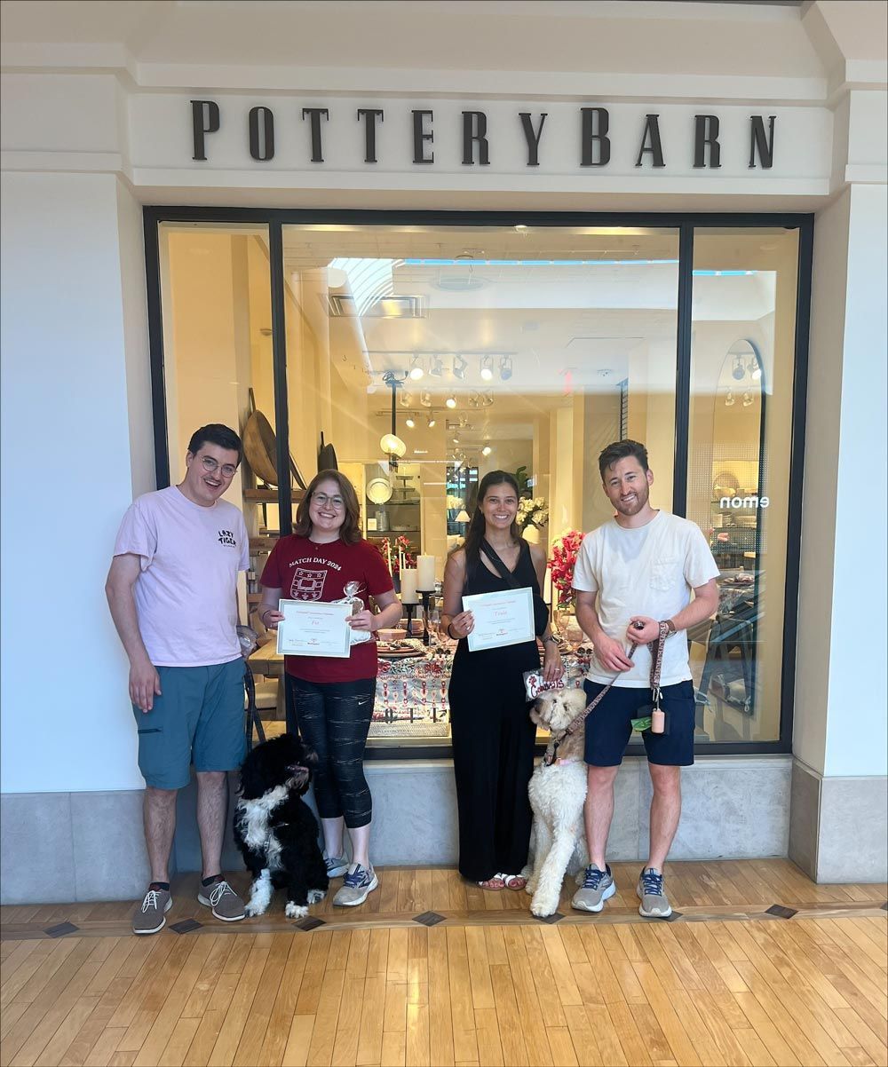 A group of people standing in front of a store called pottery barn