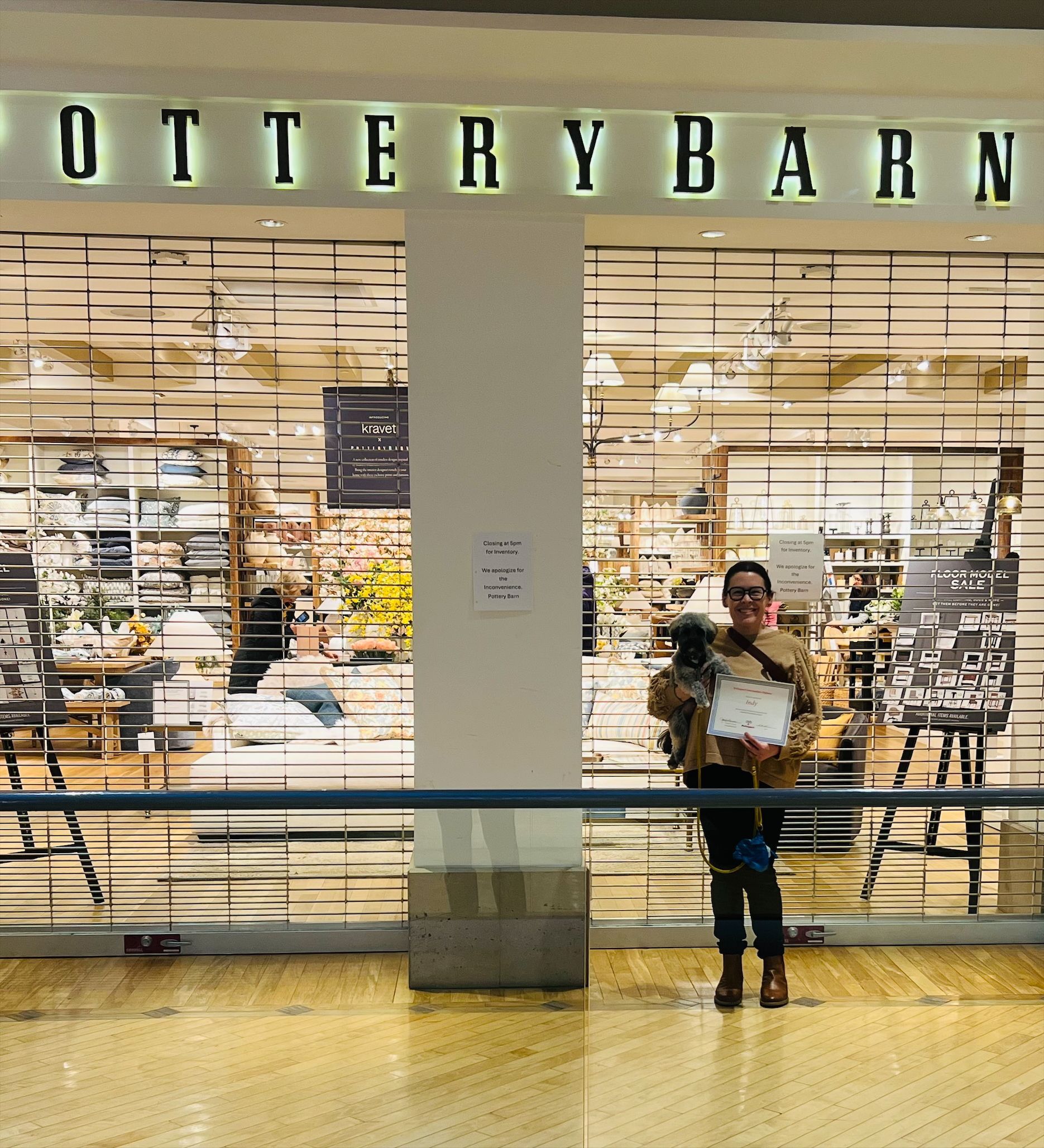 A man is standing in front of a store called pottery barn