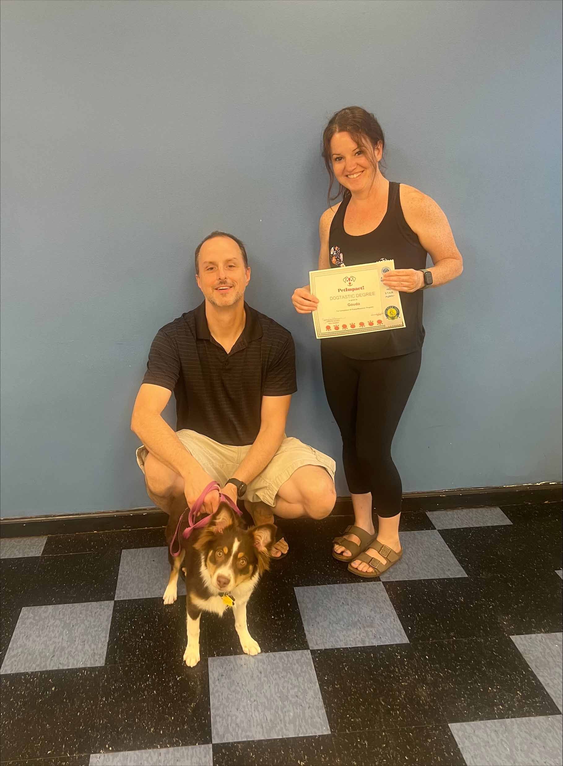 A Man And A Woman Are Posing For A Picture With A Dog