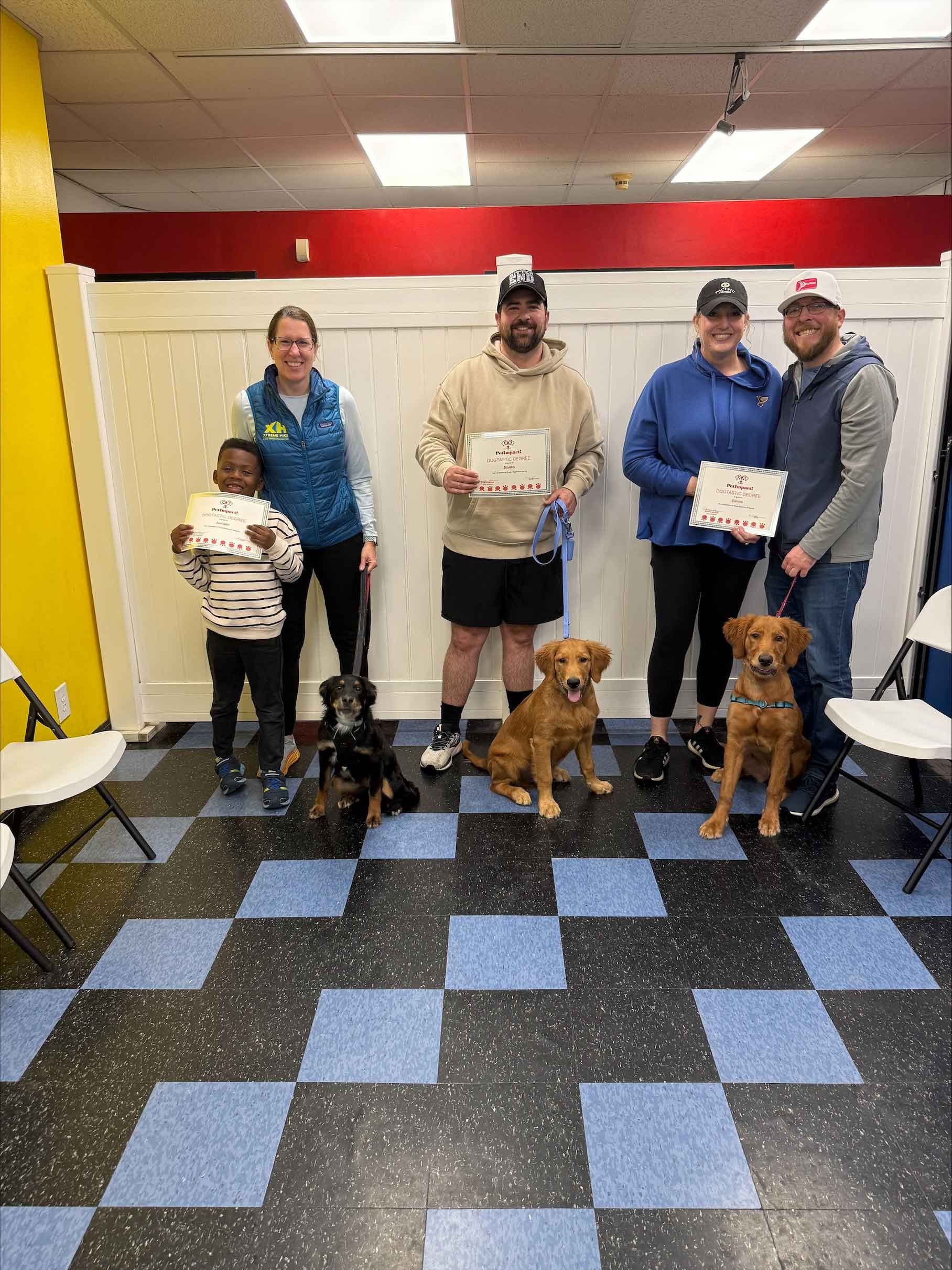 A group of people standing next to two dogs in a room.