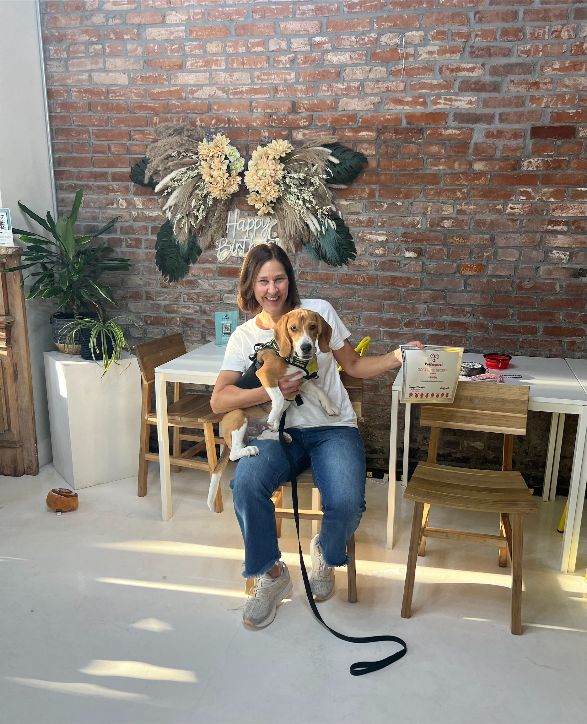 A woman is sitting in a chair holding a dog on a leash.
