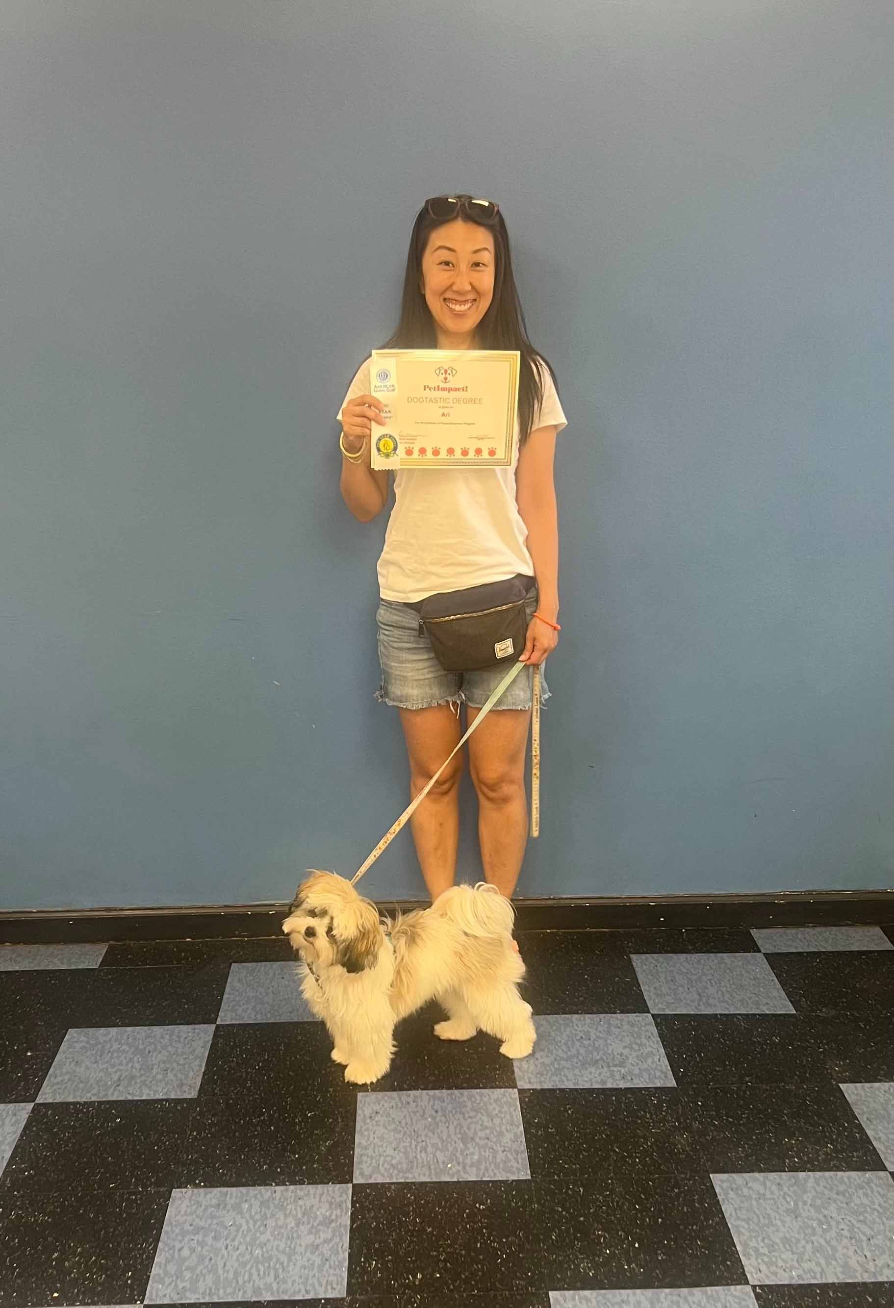 A Woman Is Standing Next To A Small Dog On A Leash And Holding A Certificate