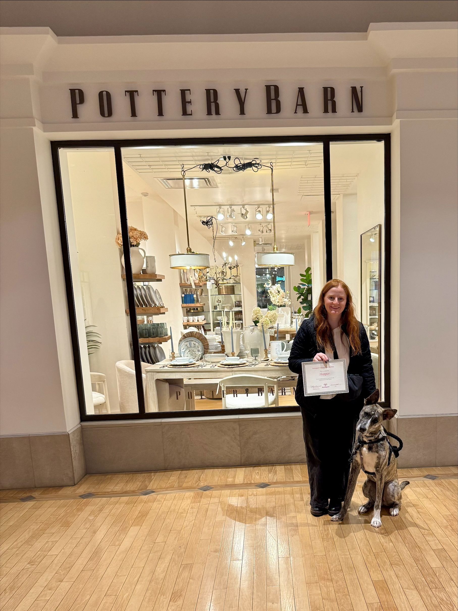 Woman with service dog stands outside Pottery Barn store.