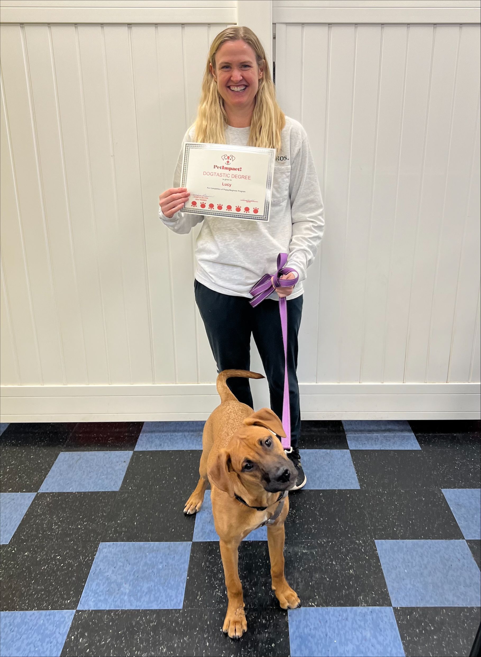 A woman is standing next to a dog on a leash and holding a sign.