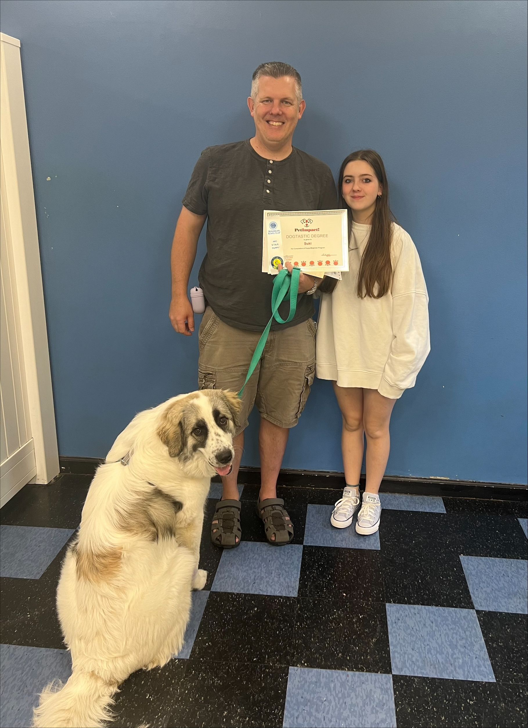 A man and a girl are standing next to a dog holding a certificate.