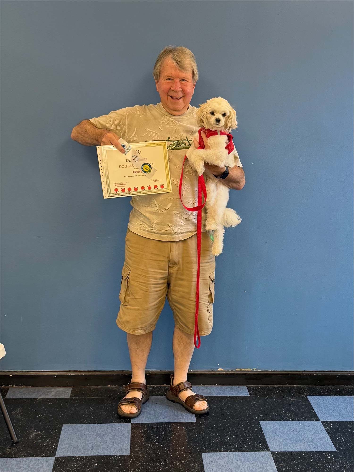 A man is holding a small white dog and a certificate.