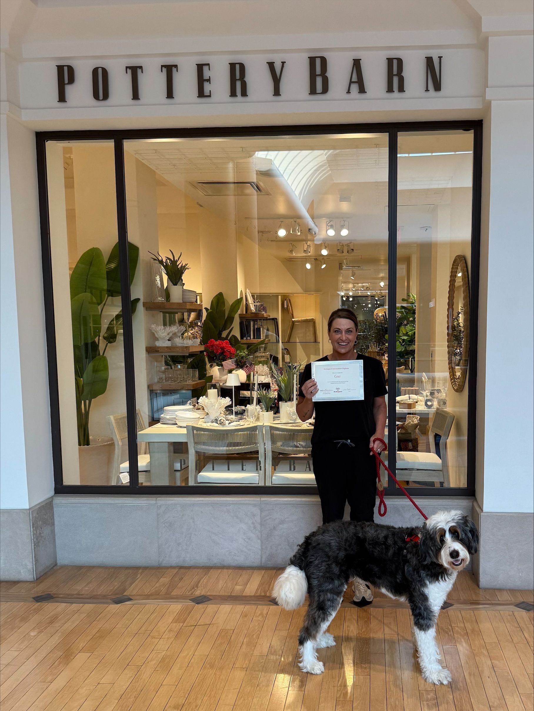 A woman and a dog are standing in front of a store called pottery barn