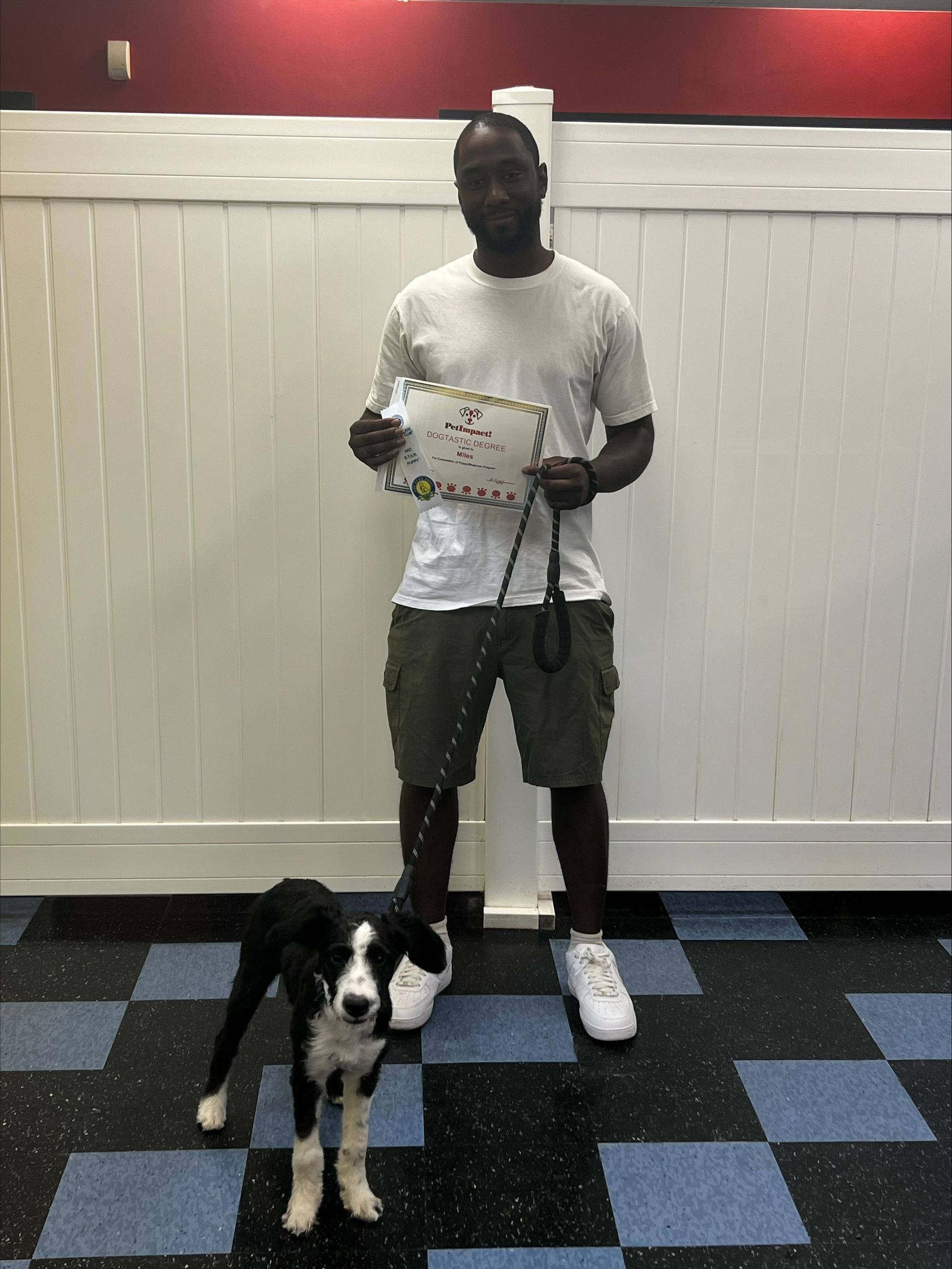 A man is standing next to a black and white dog on a leash.