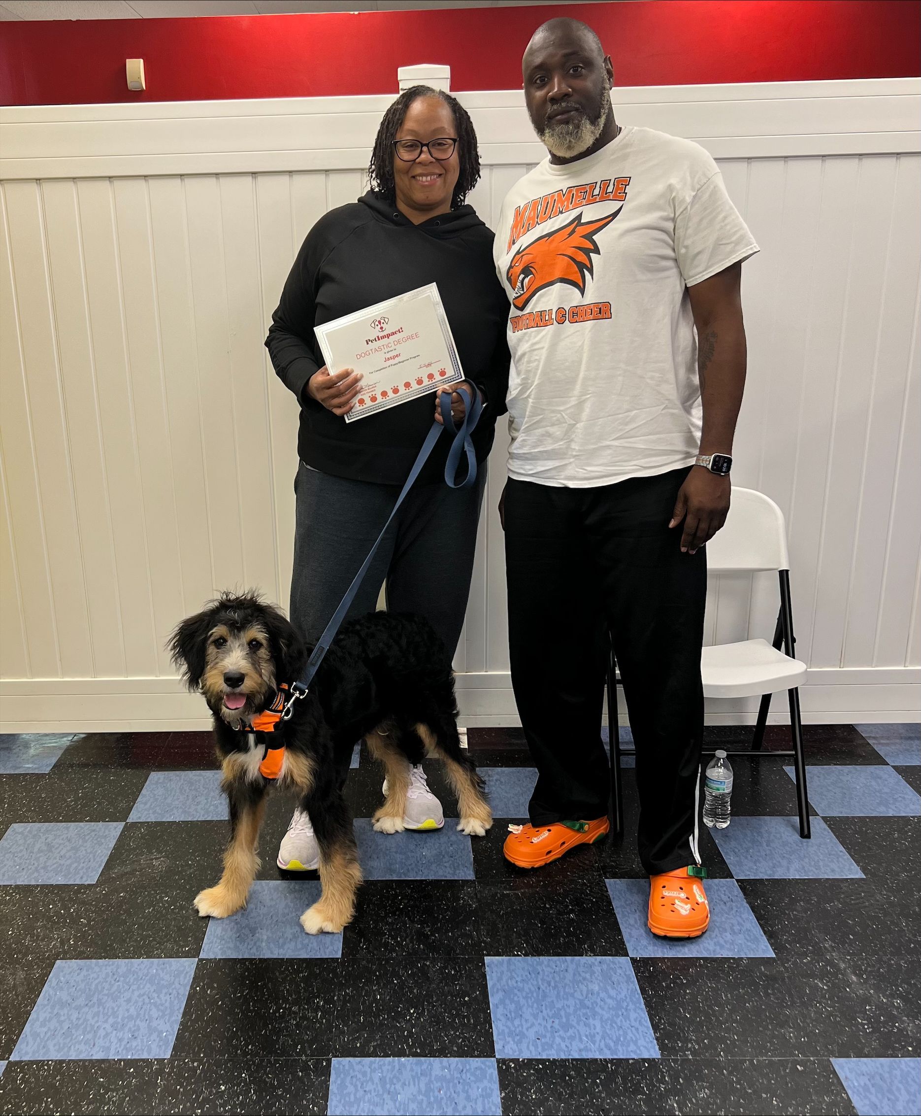 A man and a woman standing next to a dog on a leash