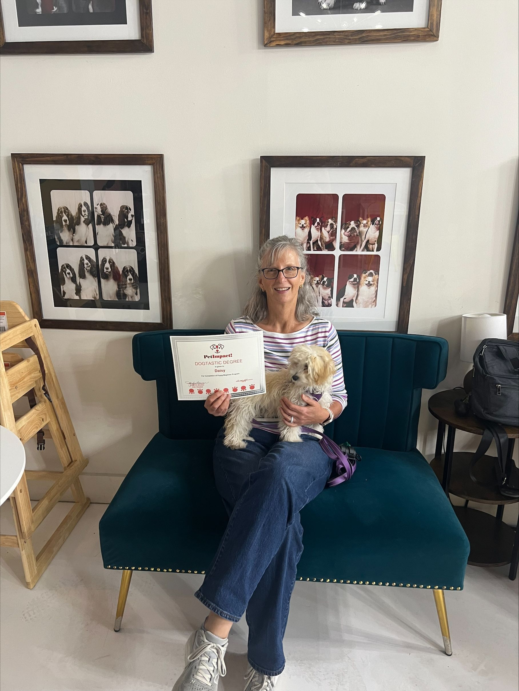 A woman is sitting on a couch holding a dog and a certificate.