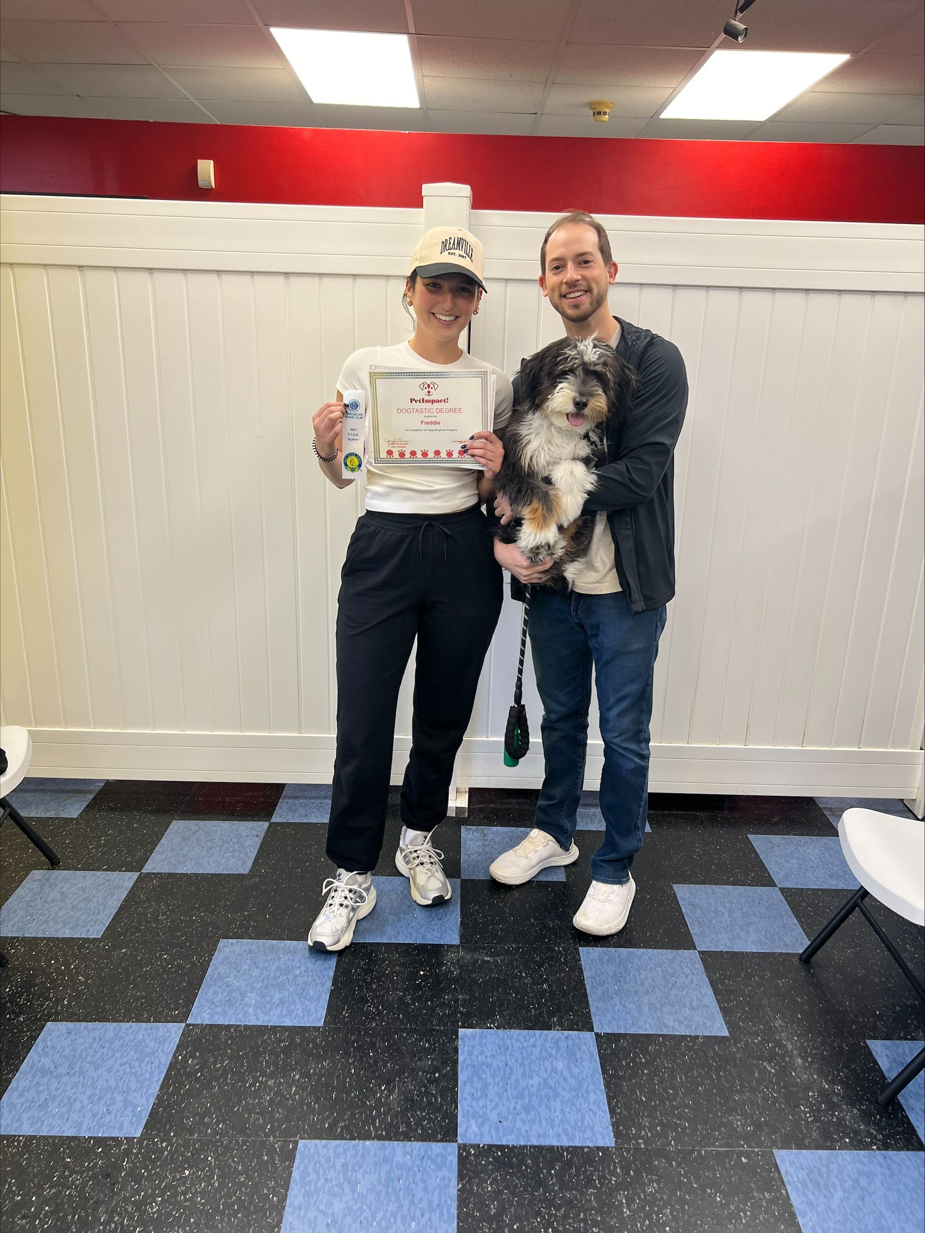 A man and a woman are standing next to each other holding a dog and a certificate.