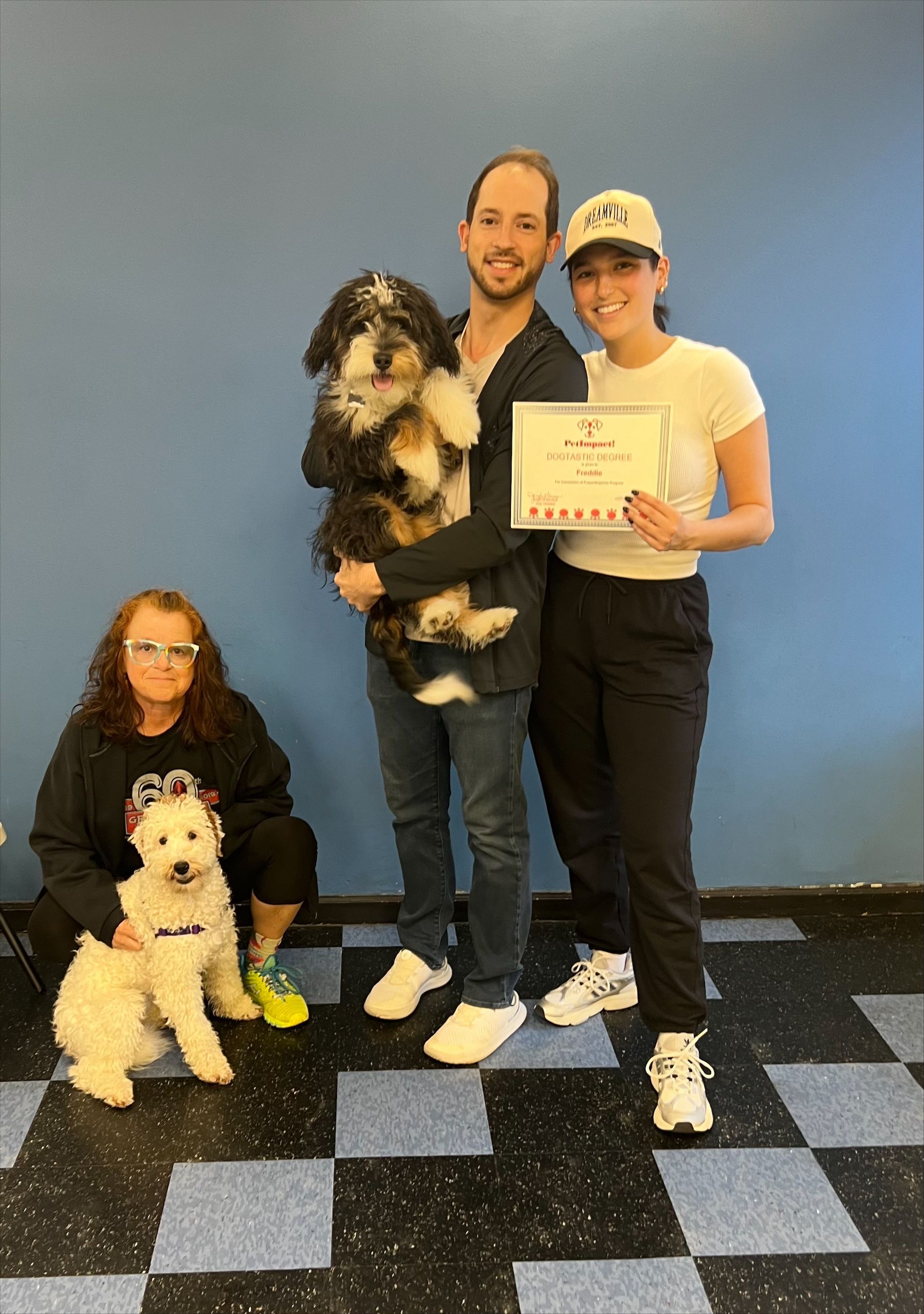 A man and a woman are standing next to two dogs and holding a certificate.