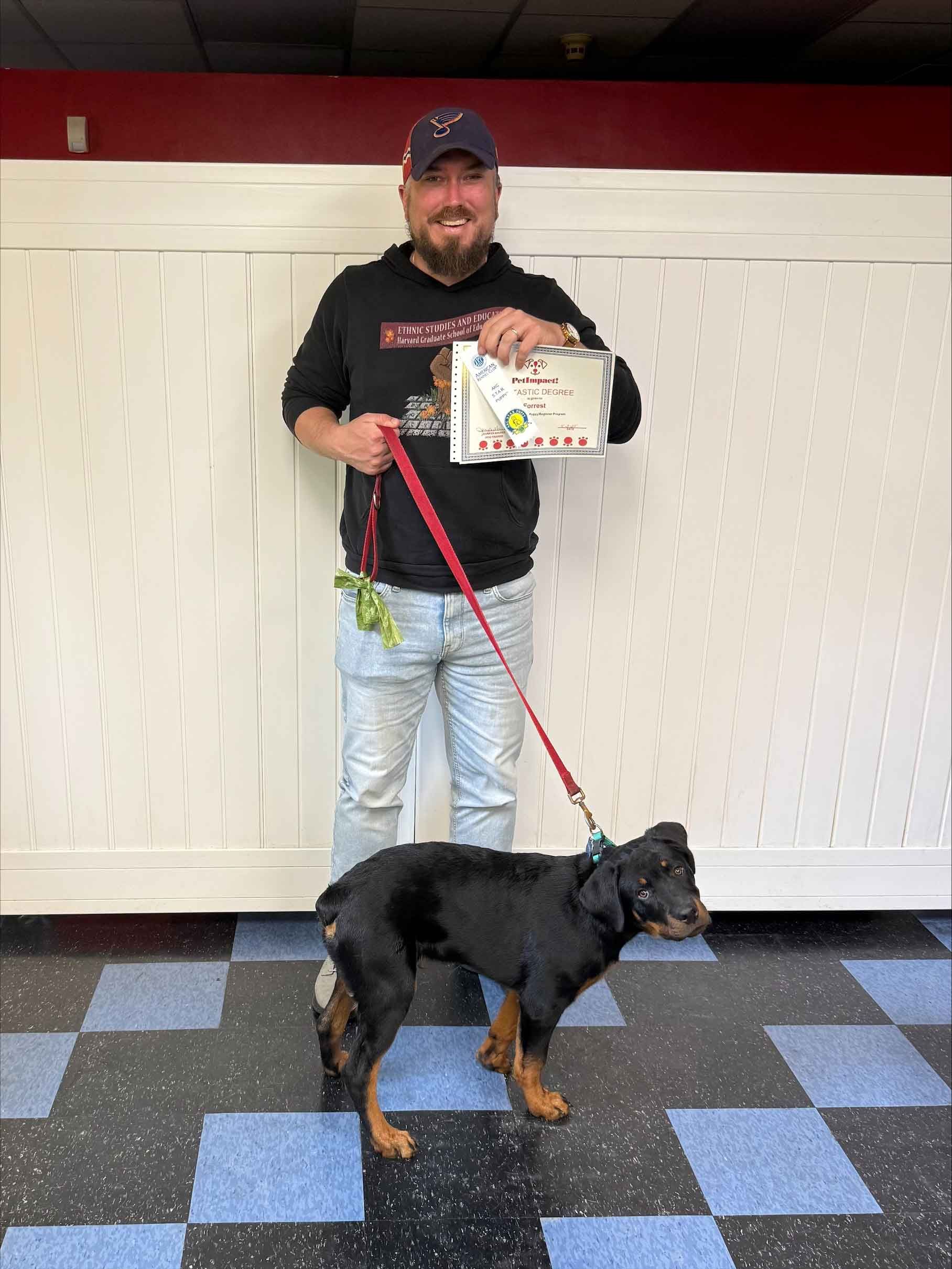 A man is standing next to a dog on a leash and holding a cake.
