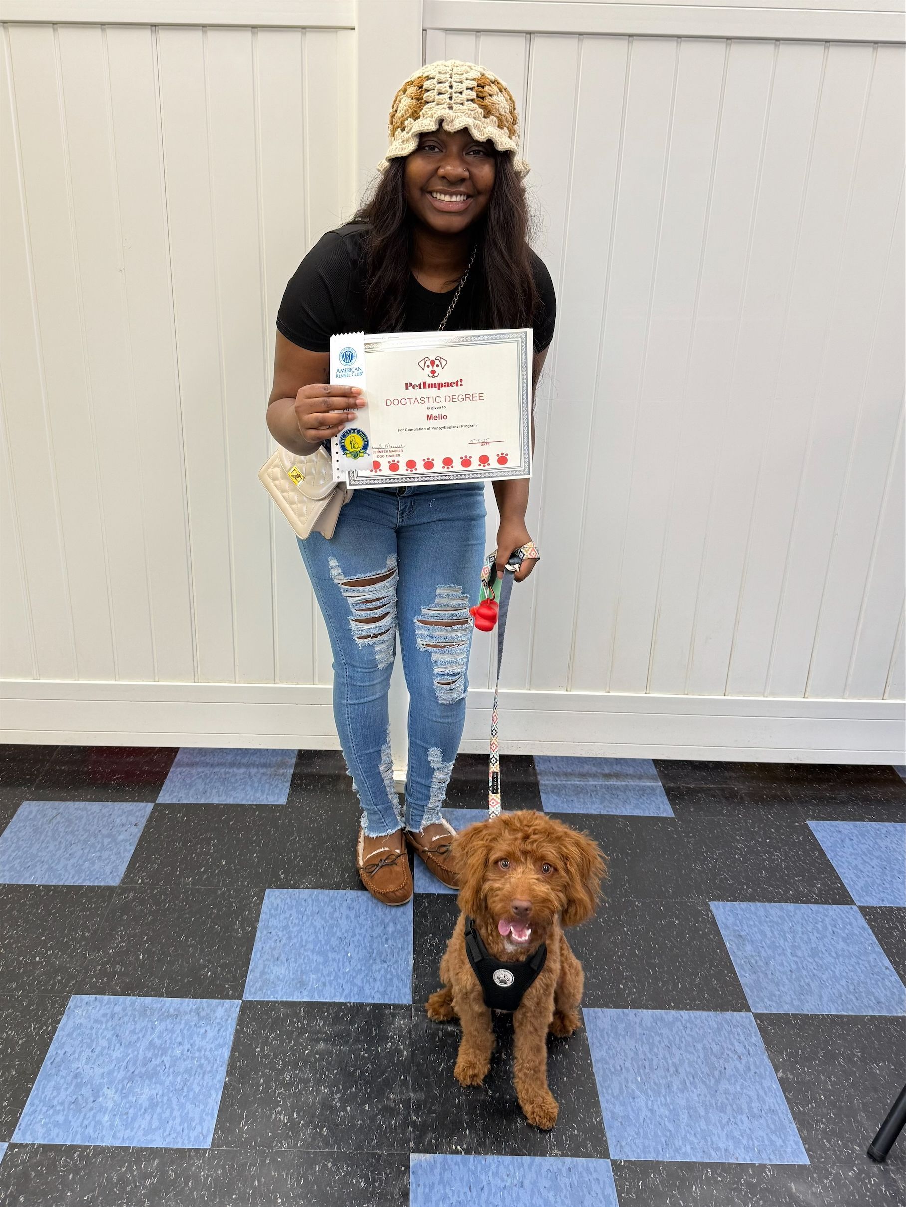 A woman is standing next to a puppy on a leash and holding a certificate.
