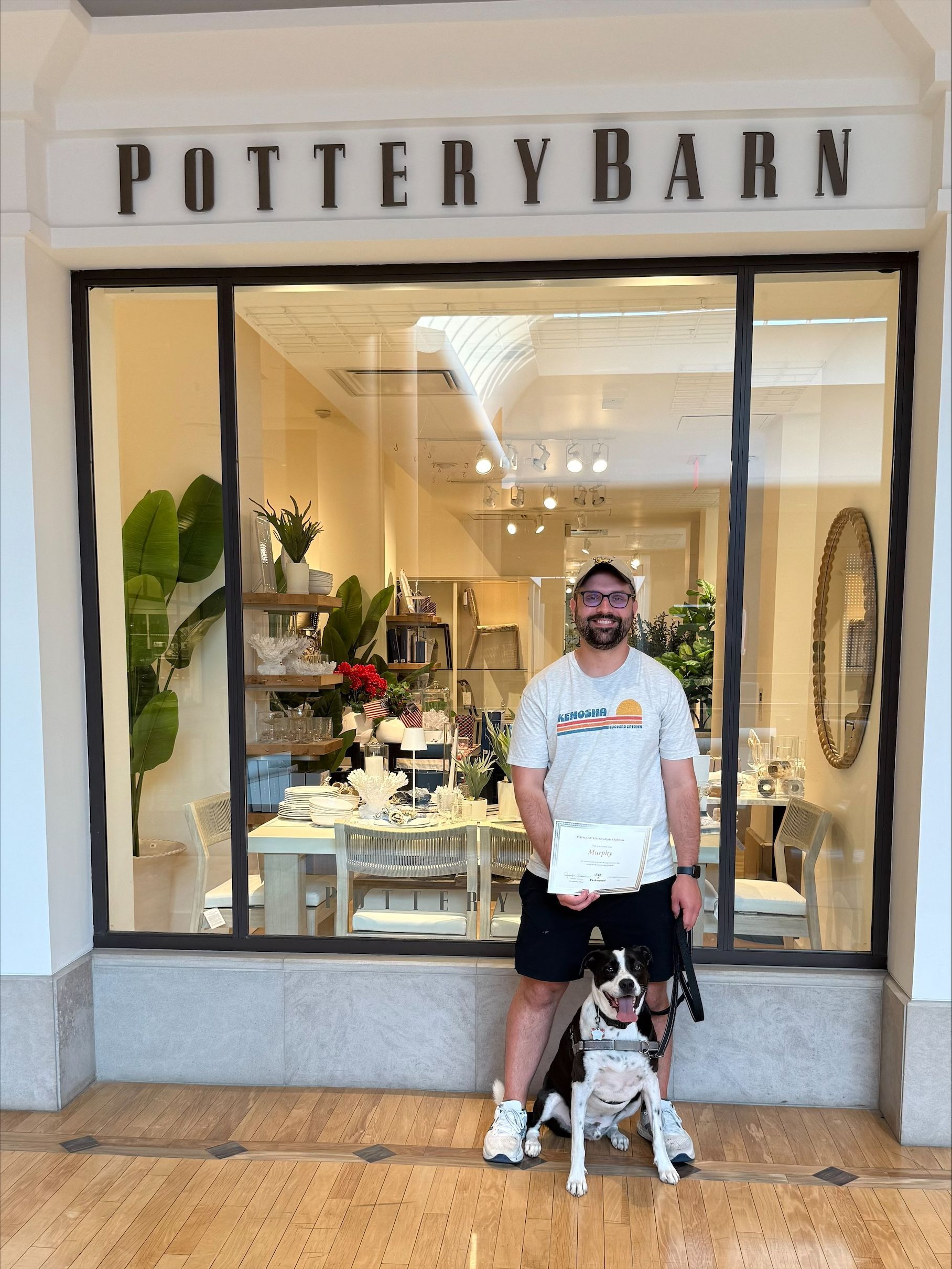 A man and a dog are standing in front of a pottery barn store.