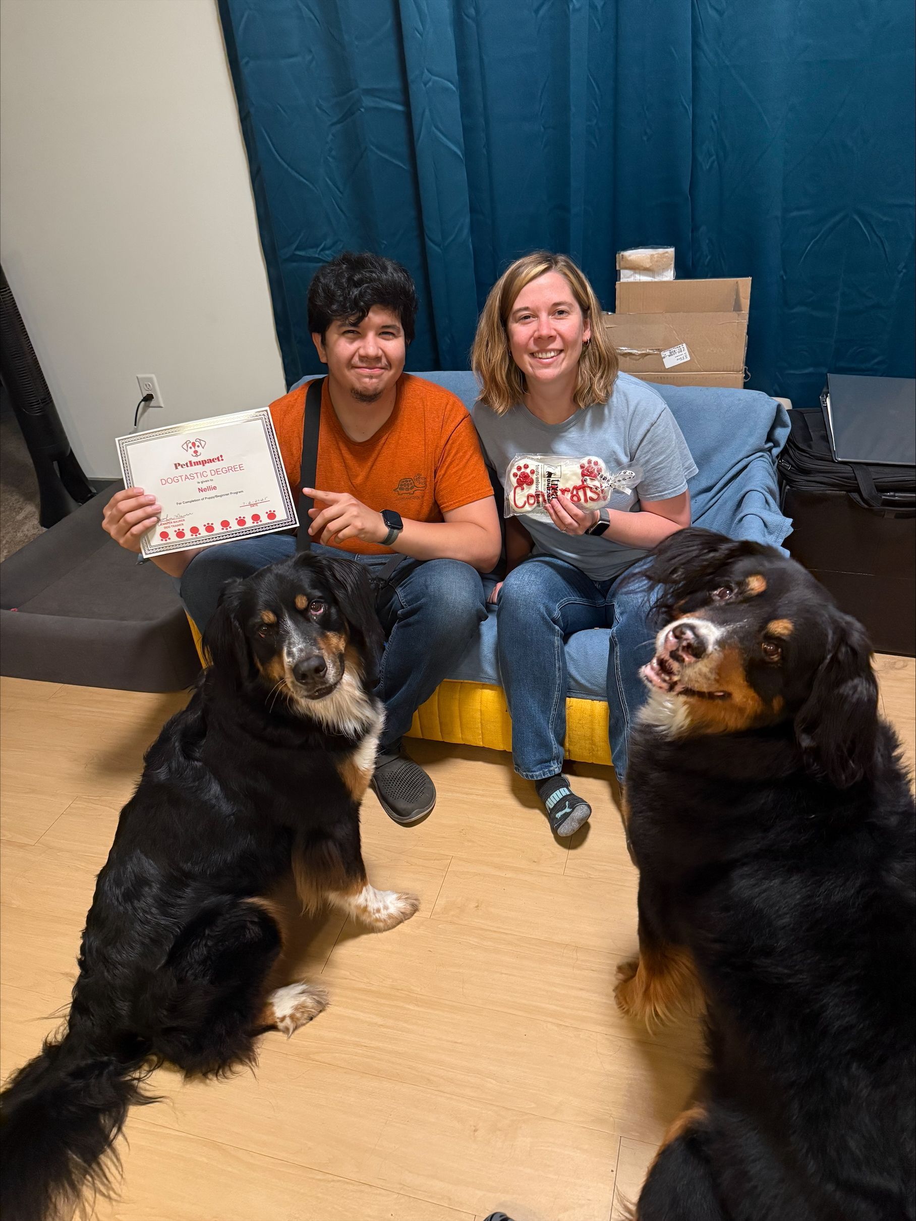 A woman is holding a small black dog and a certificate.