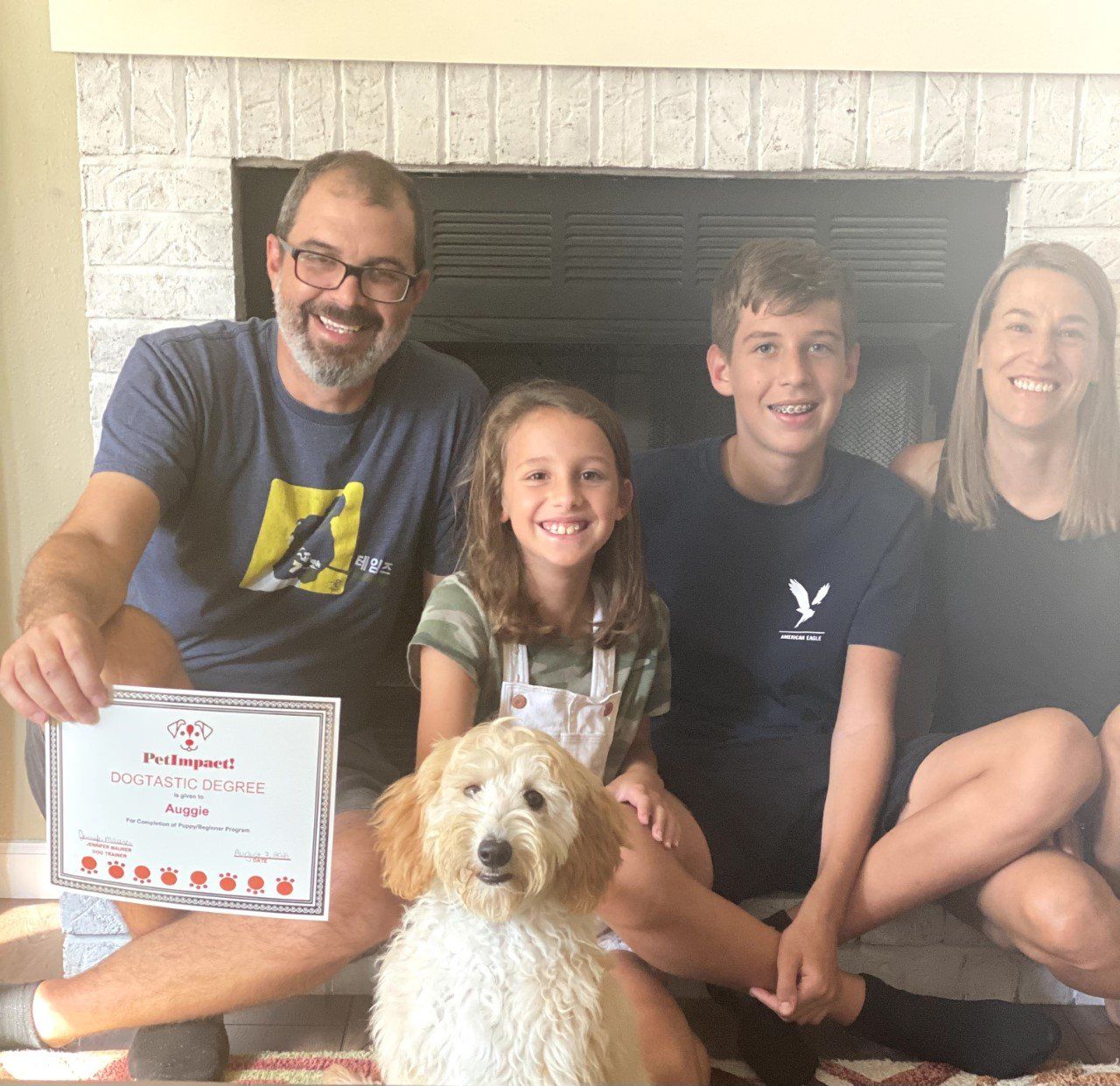 Dog Auggie With Its Family Owner Holding Certificate — St. Louis, MO — PetImpact!