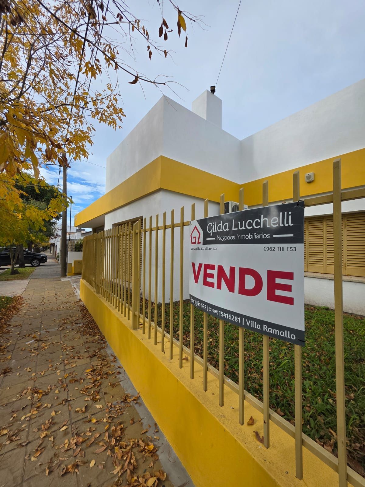 Casa con valla amarilla y cartel inmobiliario