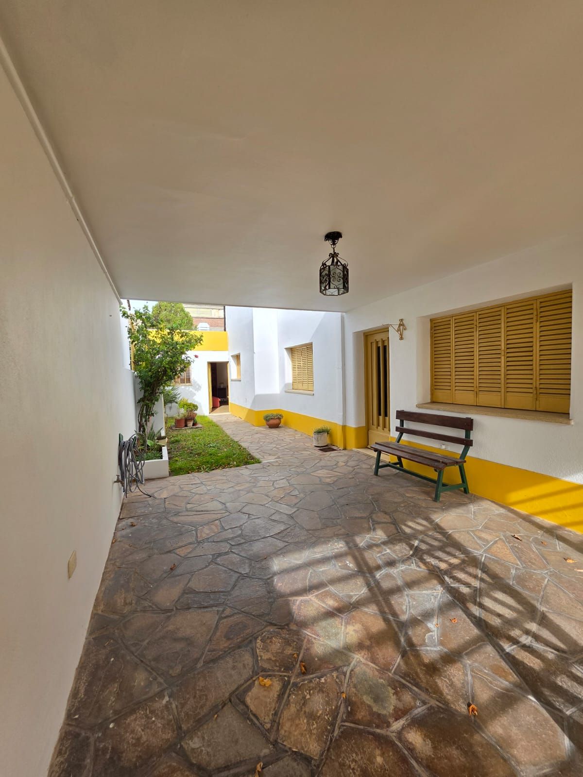 Patio cubierto con suelo de piedra, paredes con detalles amarillos