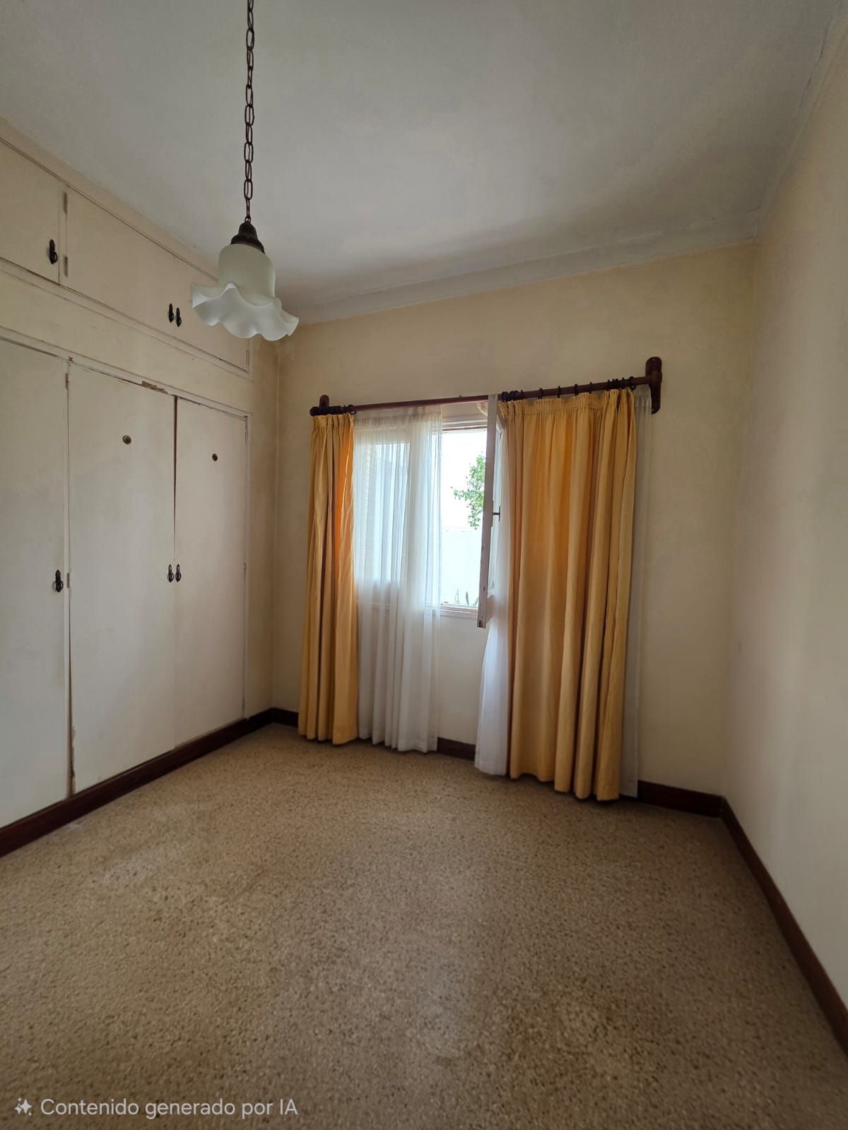 Habitación vacía con armarios empotrados, alfombra beige y cortinas amarillas sobre una puerta con ventana.
