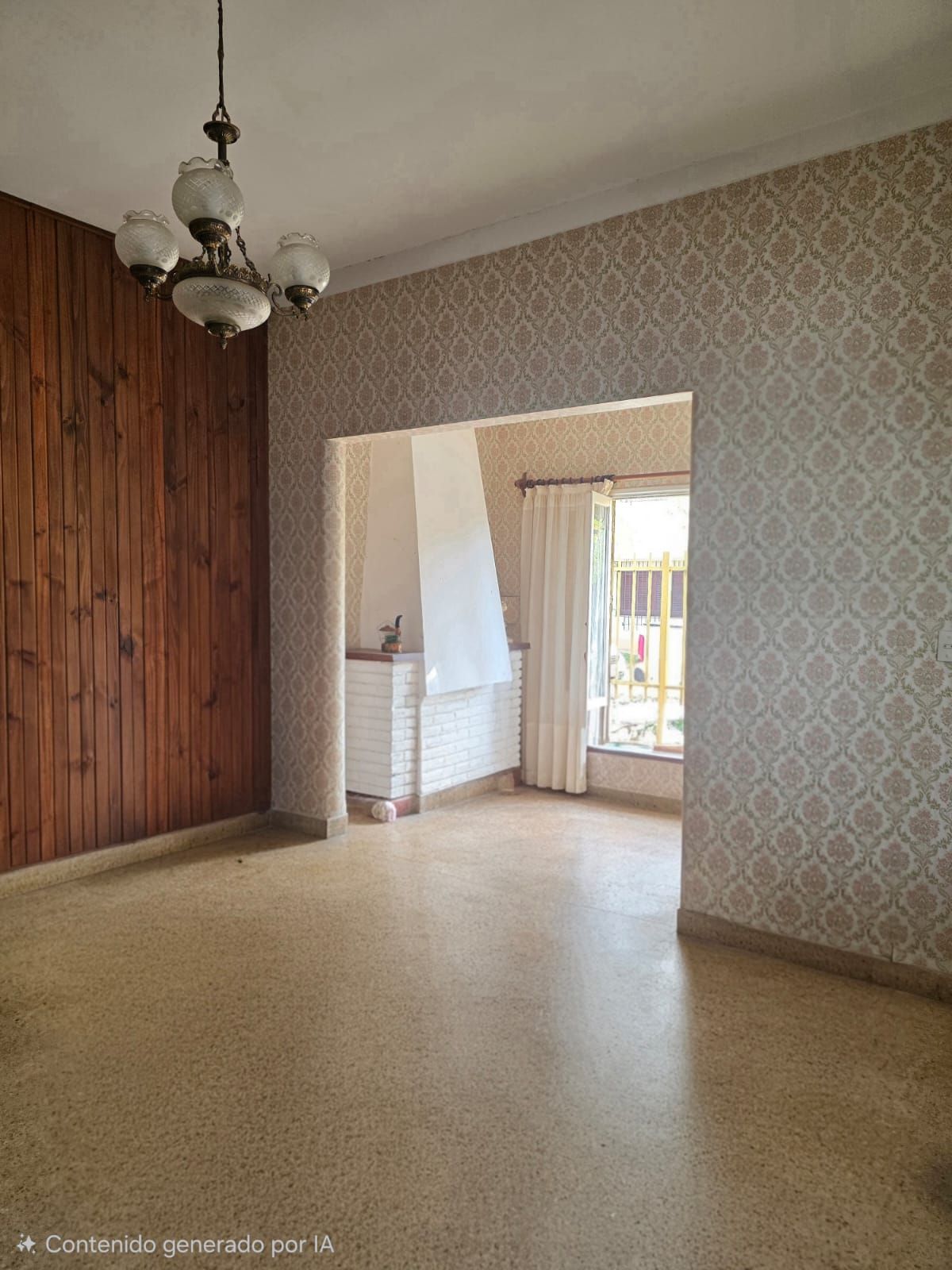 Sala de estar vacía con papel tapiz estampado, pared revestida de madera y puerta que da a una habitación contigua luminosa.