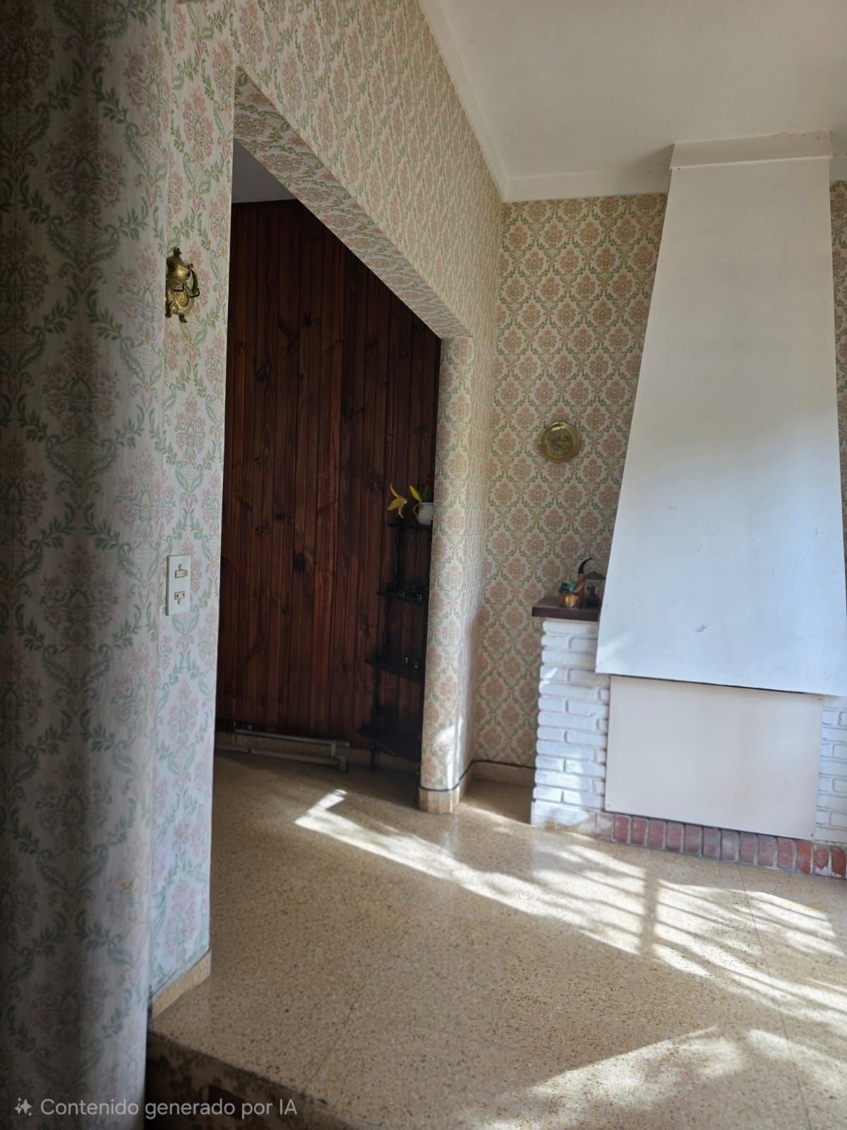 Pasillo luminoso con papel pintado estampado, puerta abierta y repisa de chimenea blanca.