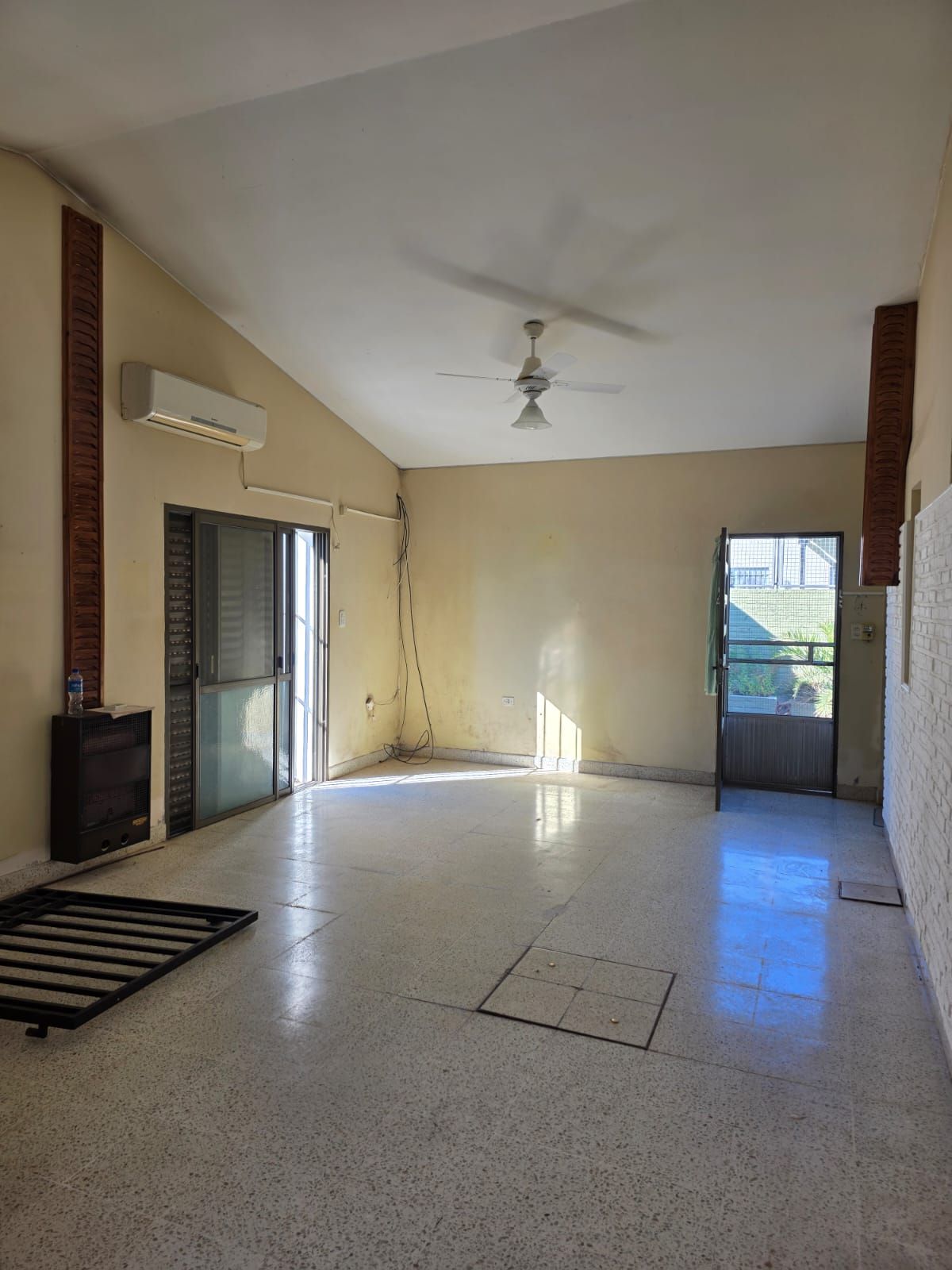 Sala de estar vacía de color beige con piso de baldosas, ventilador