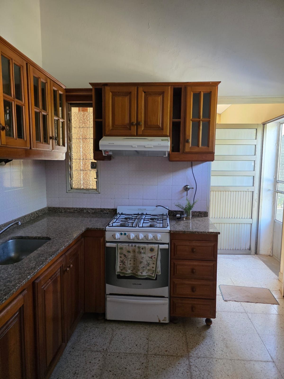 Pequeña cocina con armarios de madera, estufa de gas