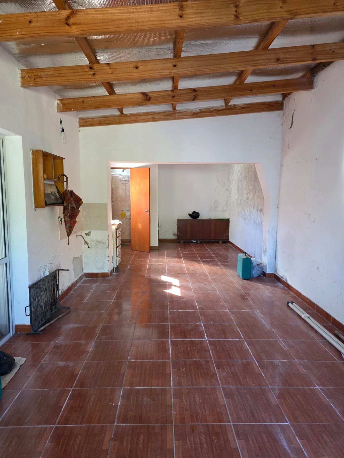 Habitación vacía con suelo de baldosas de terracota, paredes