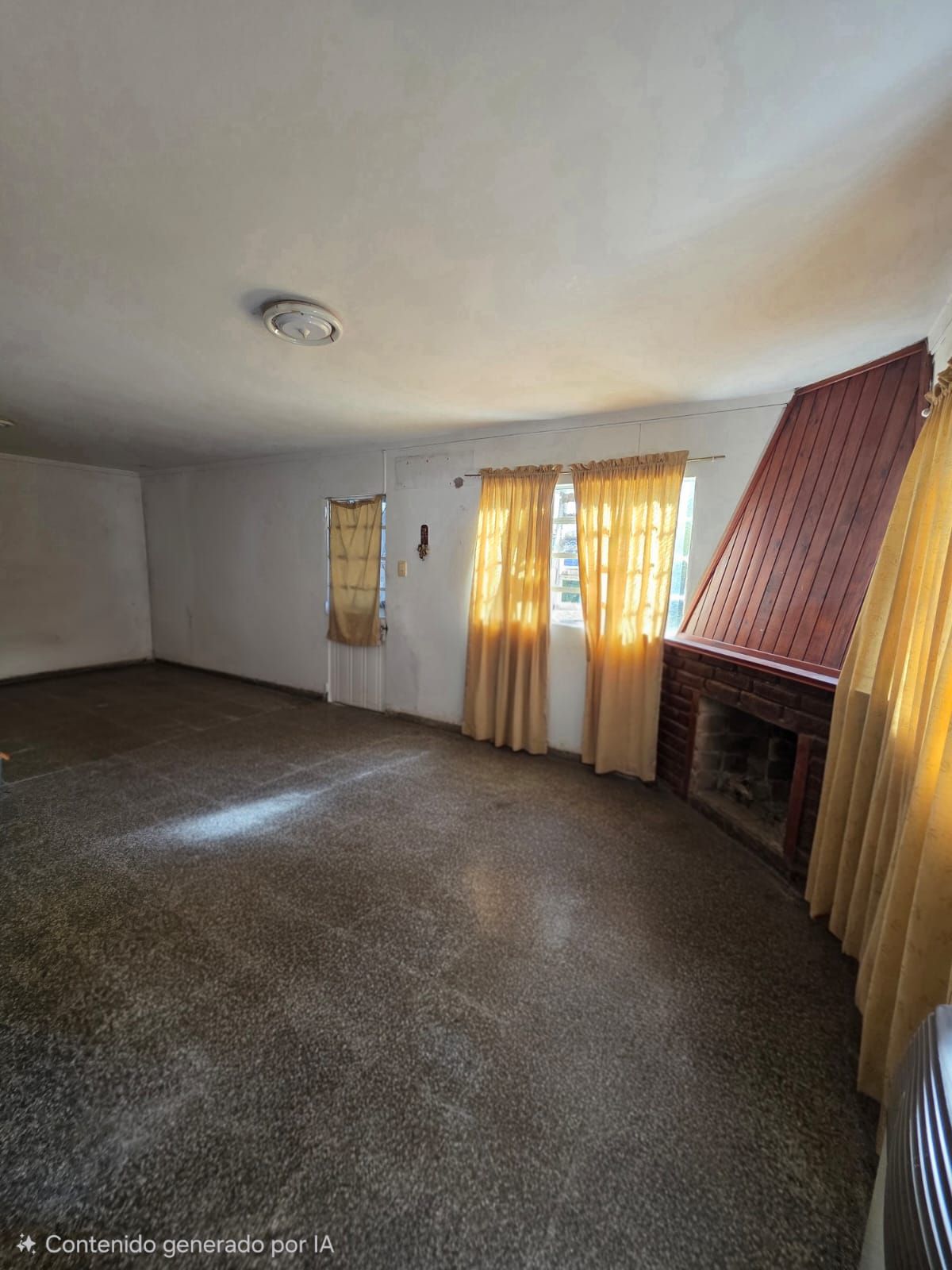 Sala de estar vacía con alfombra marrón, paredes blancas y cortinas amarillas junto a las ventanas.