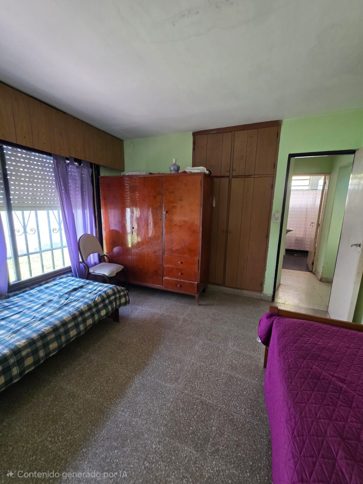 Habitación pequeña con cama, armario, ventana y puerta, con paredes verdes y detalles en color púrpura.