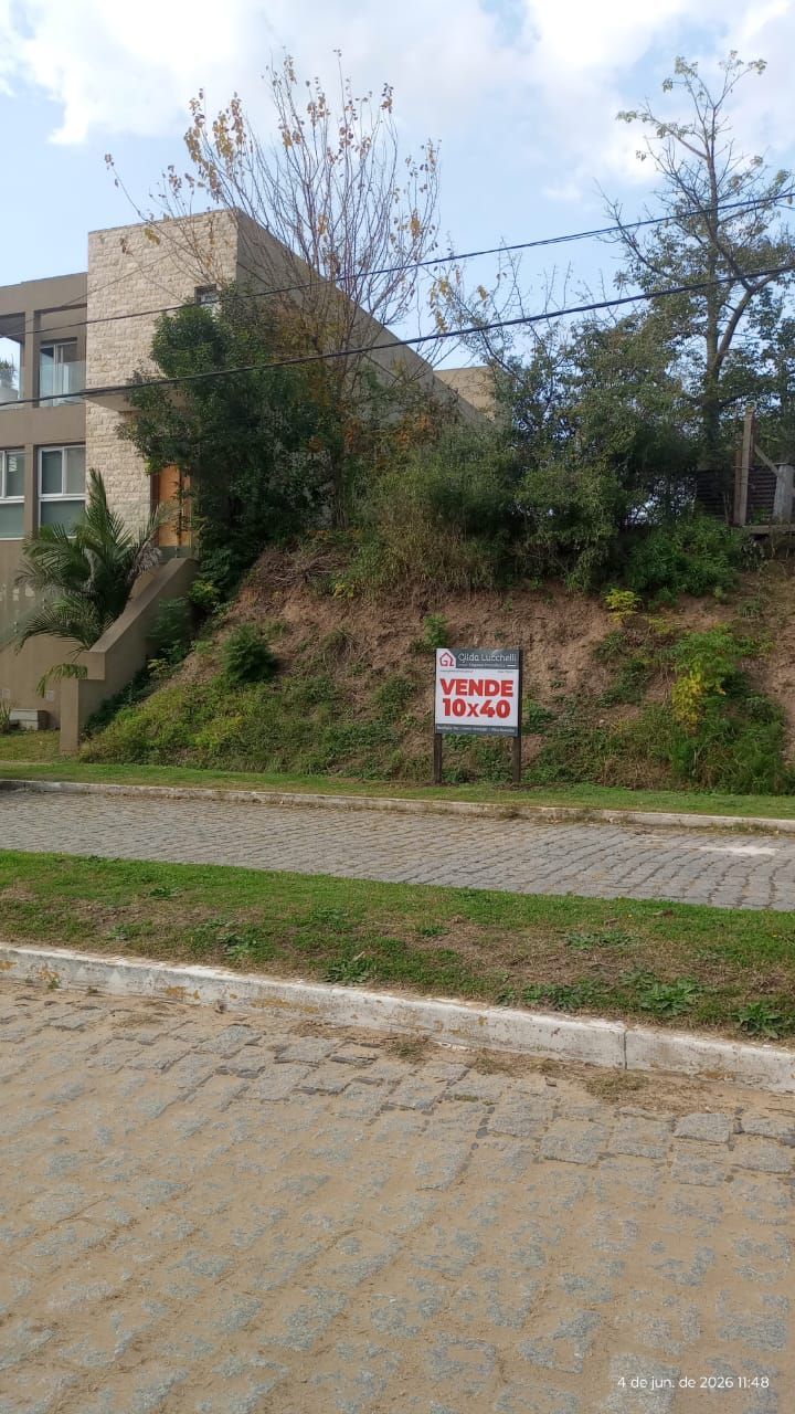 Un cartel verde indica que se vende una casa pequeña de color verde menta al atardecer.