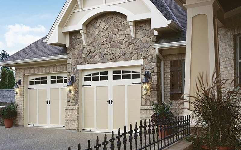 Two-car garage with beige doors, stone facade, and black hardware.