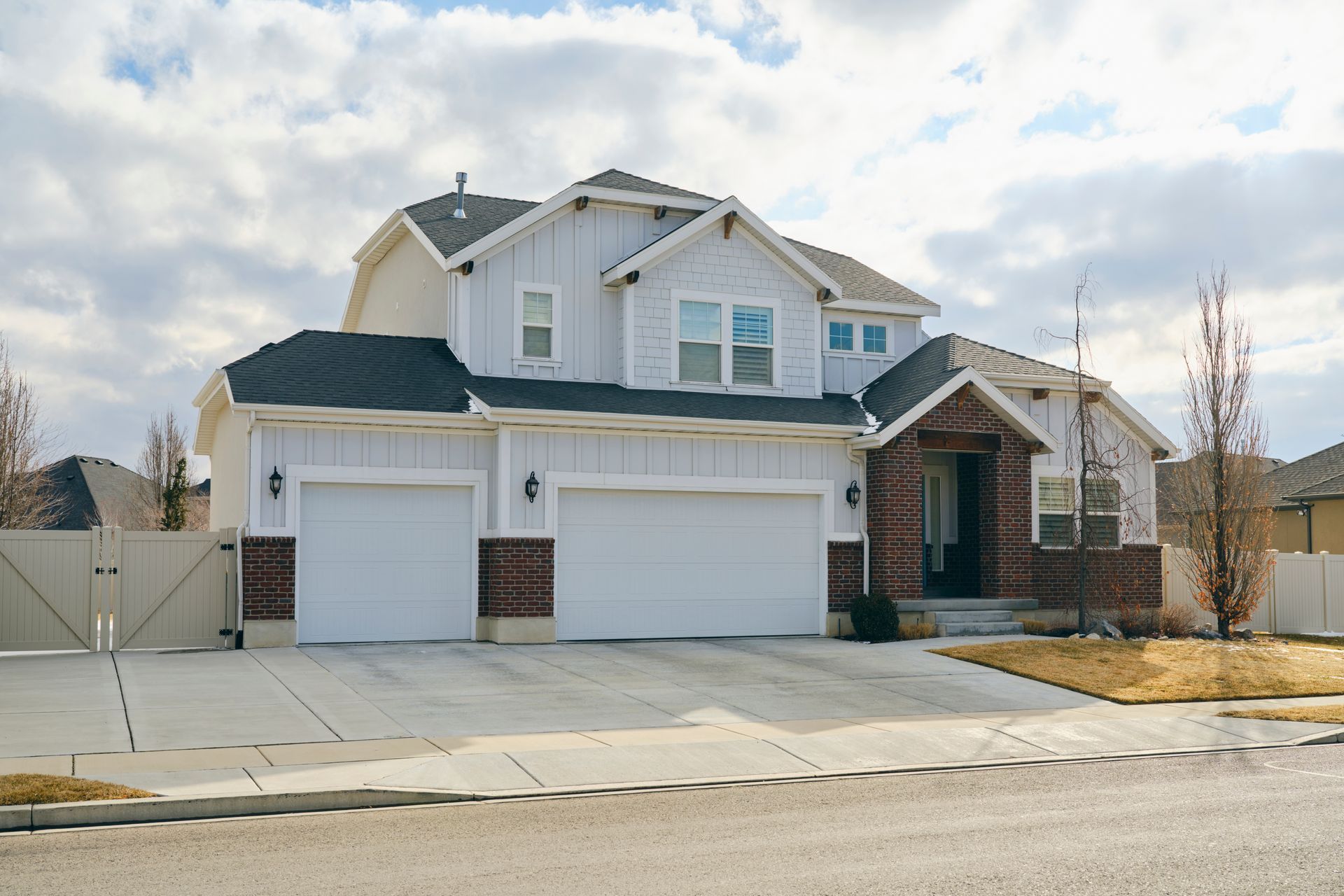 Two-story white house with brick accents, two-car garage, and driveway.