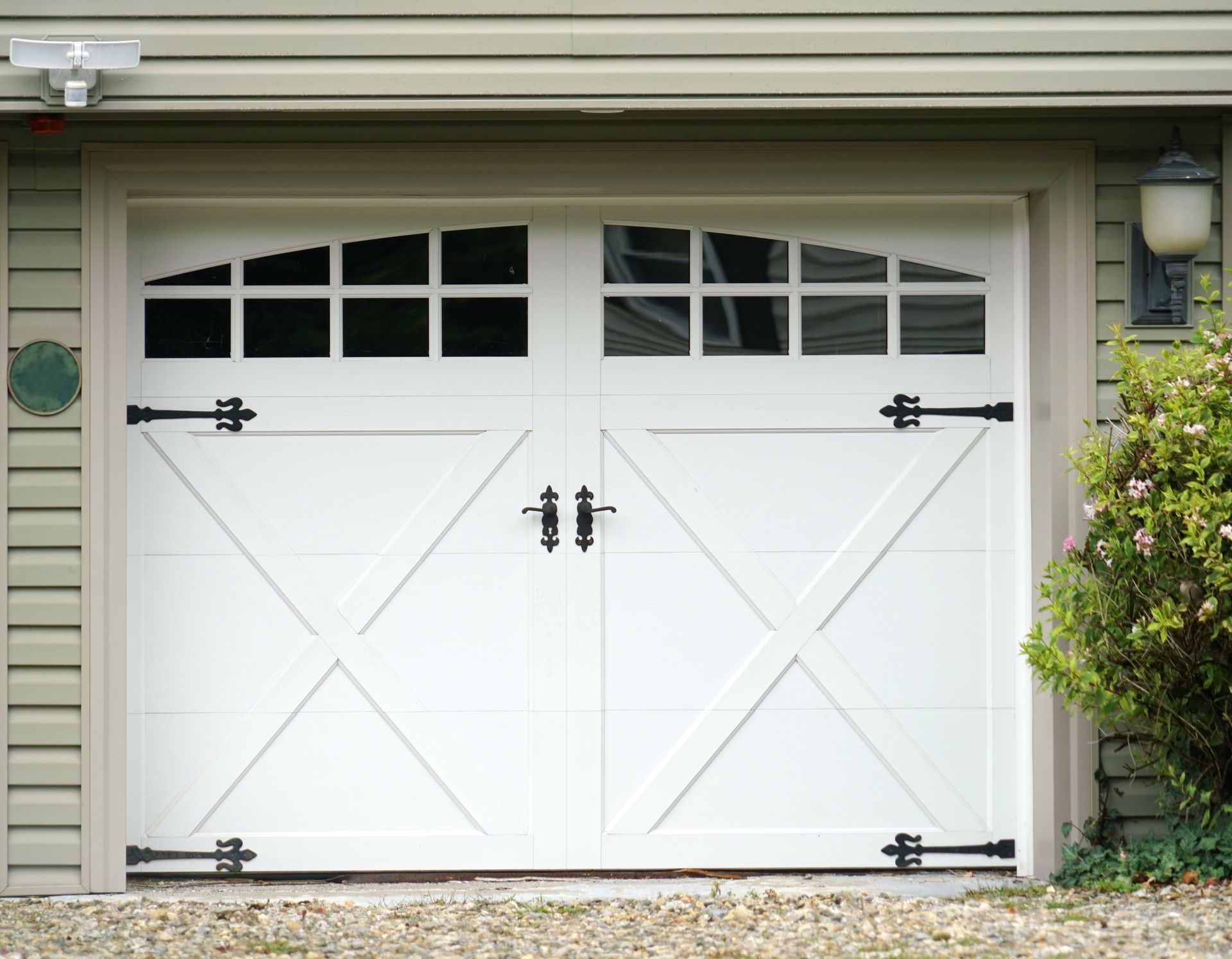 White double garage doors with black hardware and window paneling.